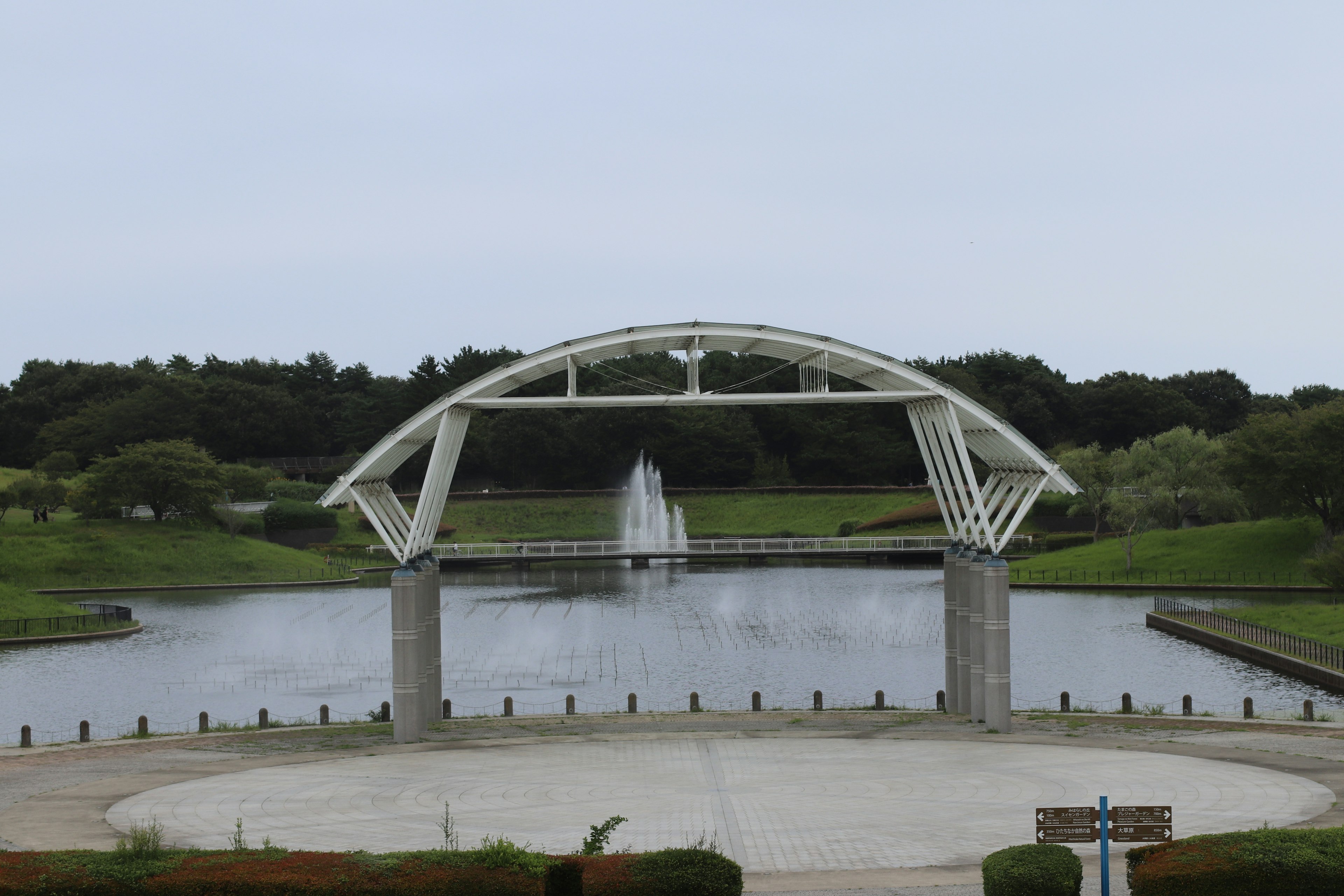 公園的風景，池塘和拱形橋，中央有噴泉，四周被綠地環繞