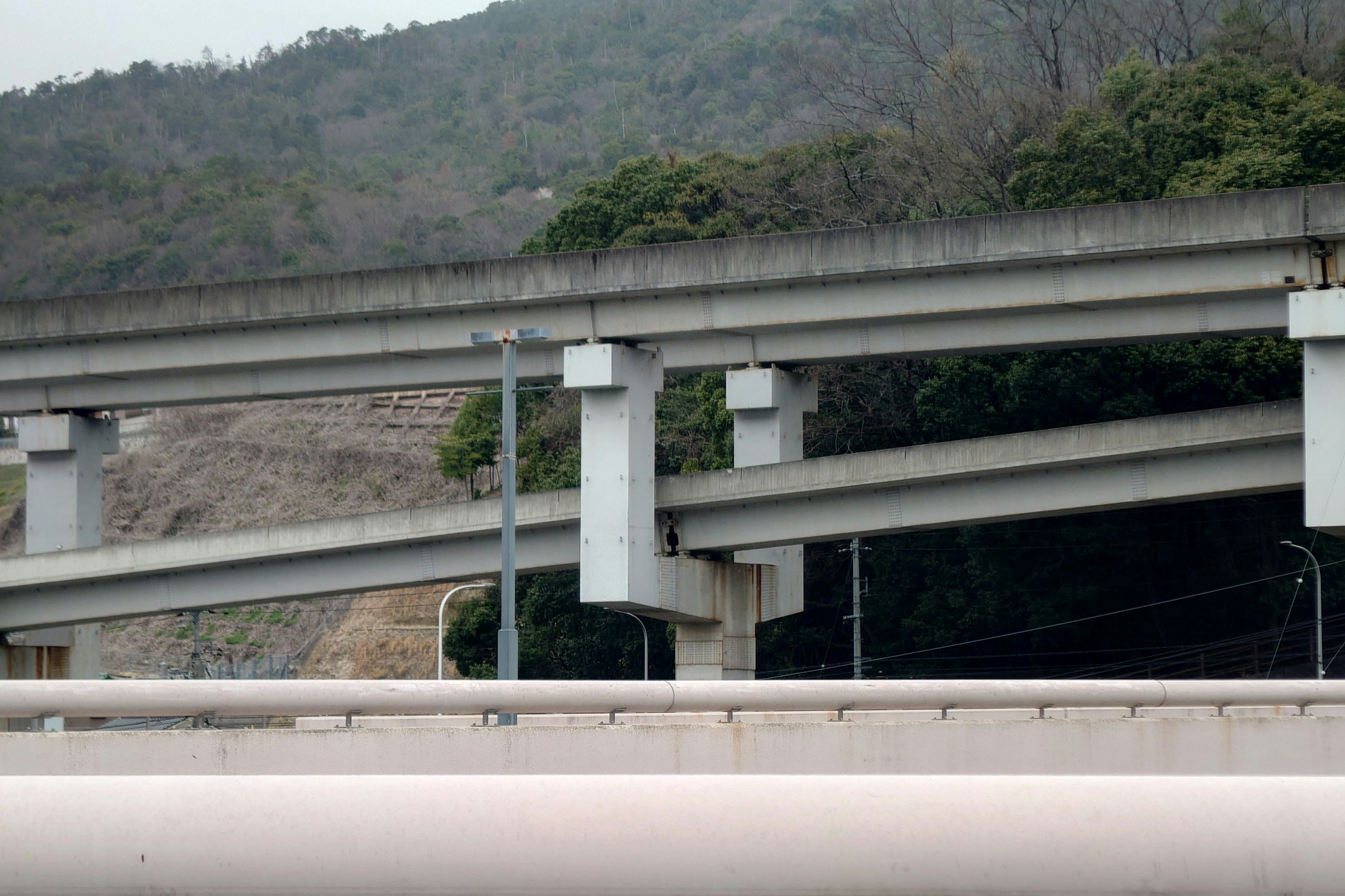 Estructura de paso elevado de concreto con colinas verdes al fondo