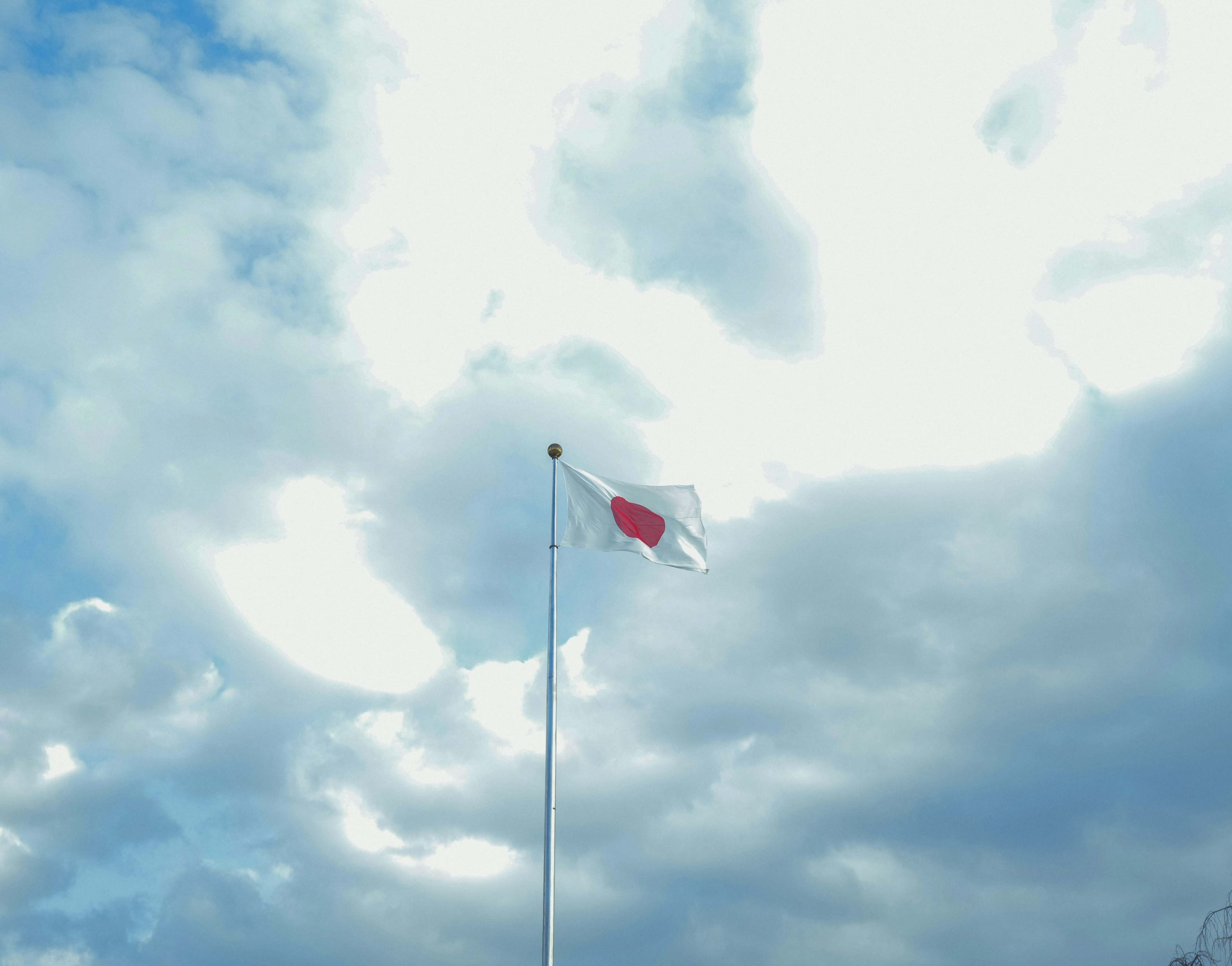 Japanese flag waving against a backdrop of blue sky and clouds