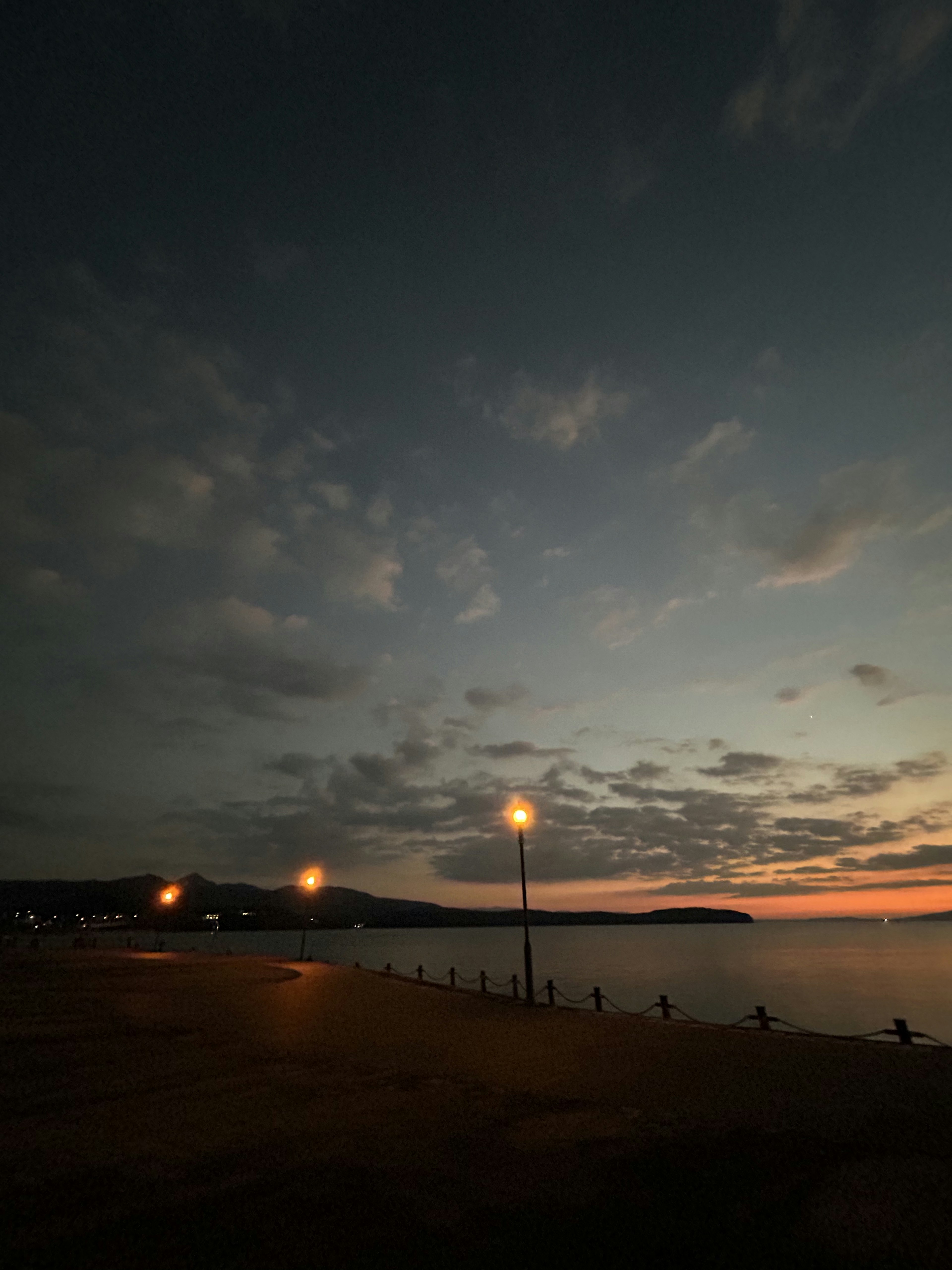 夕暮れの海岸にある街灯と静かな水面が映る風景