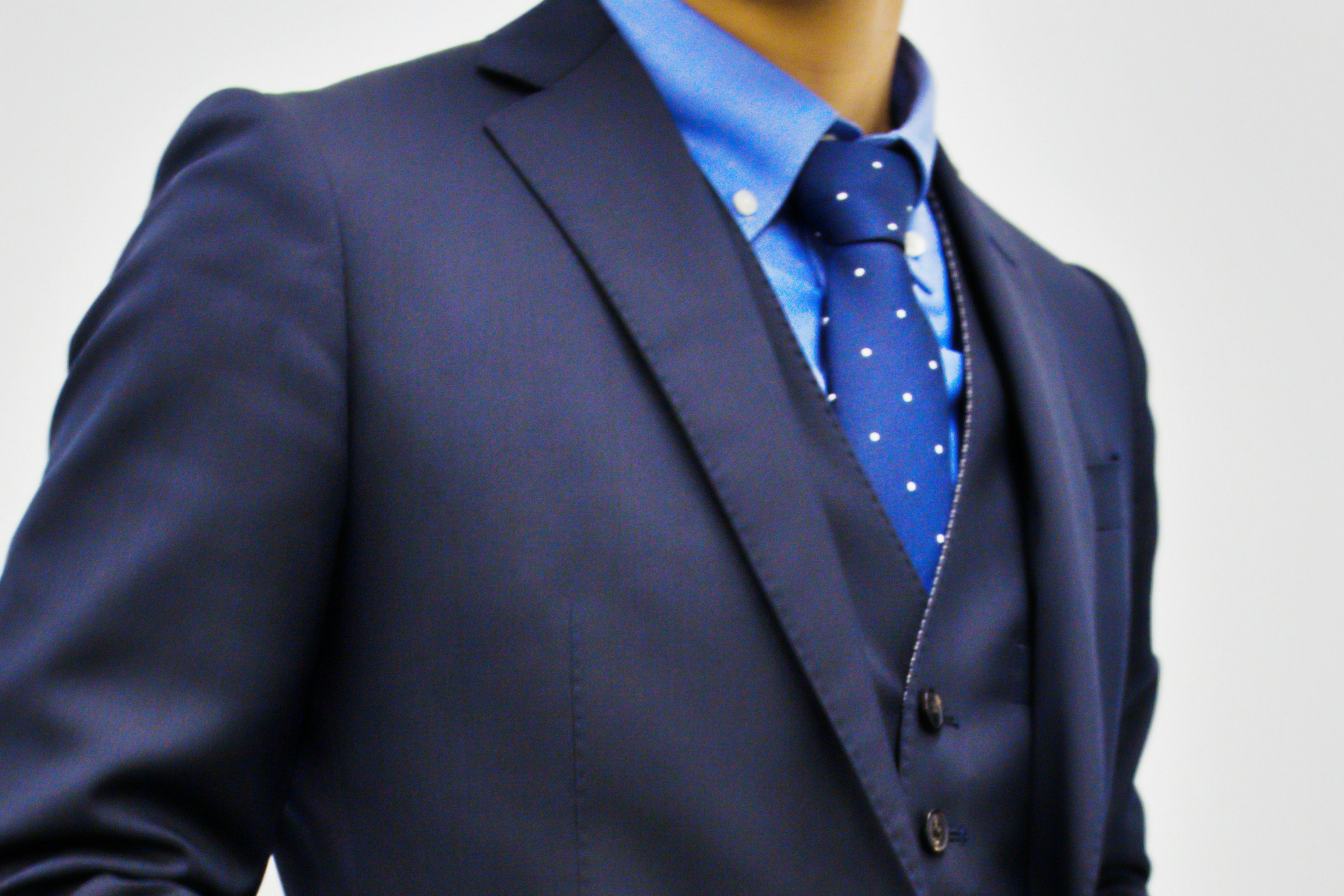 Close-up of a man in a suit featuring a blue shirt and polka dot tie