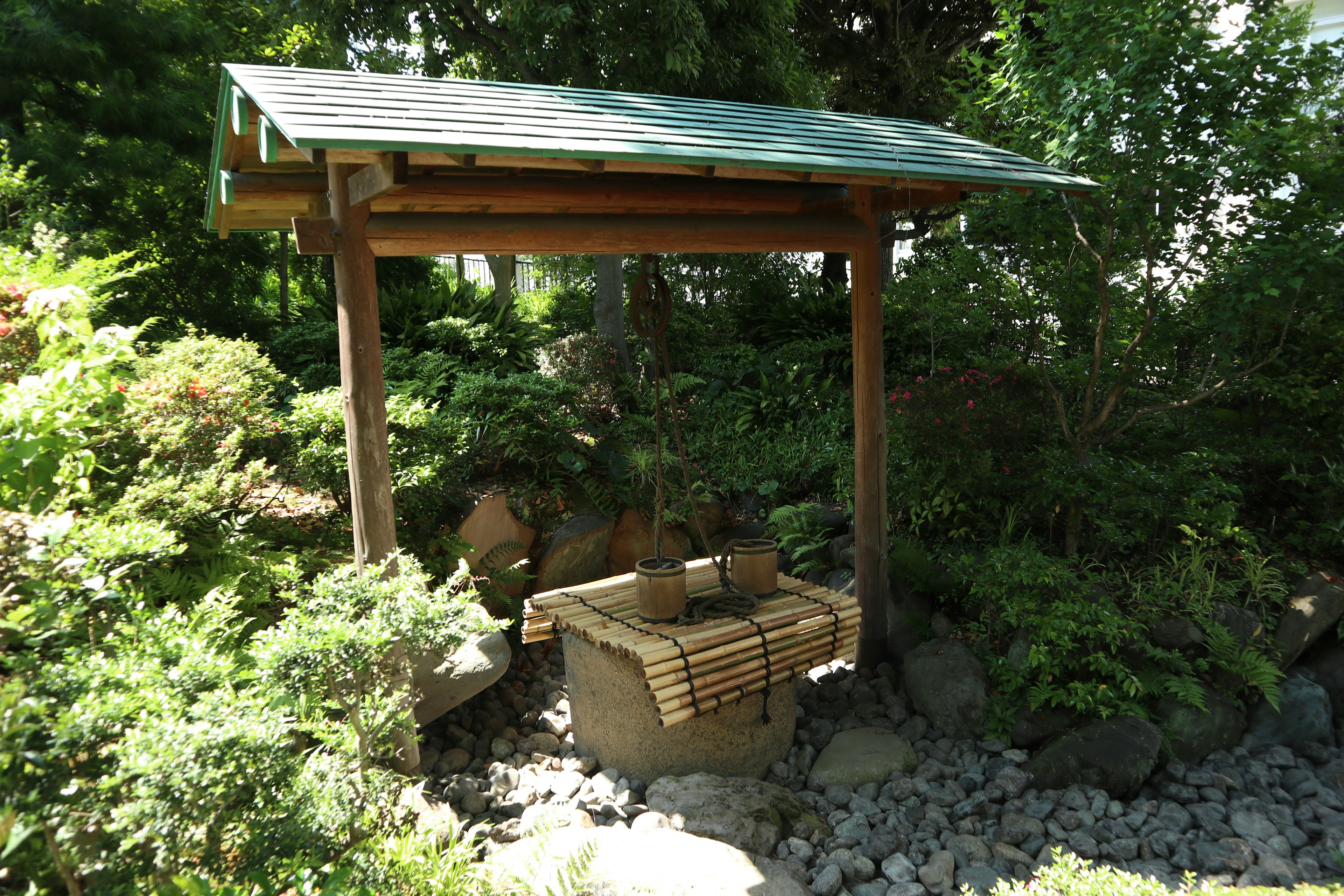 Una estructura tradicional de estanque de agua en un jardín rodeado de exuberante vegetación