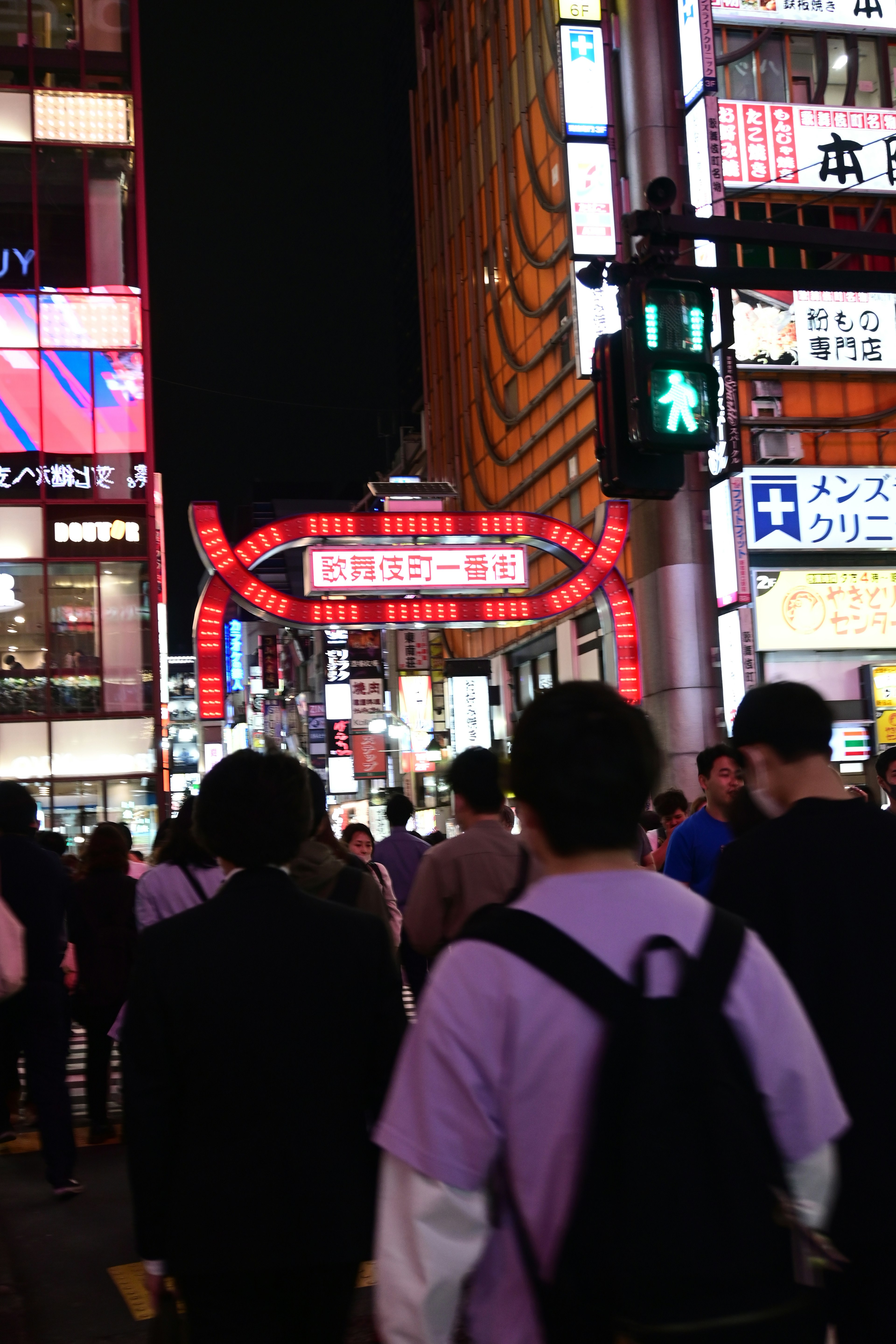 People walking in a vibrant nightlife scene with bright red neon signs