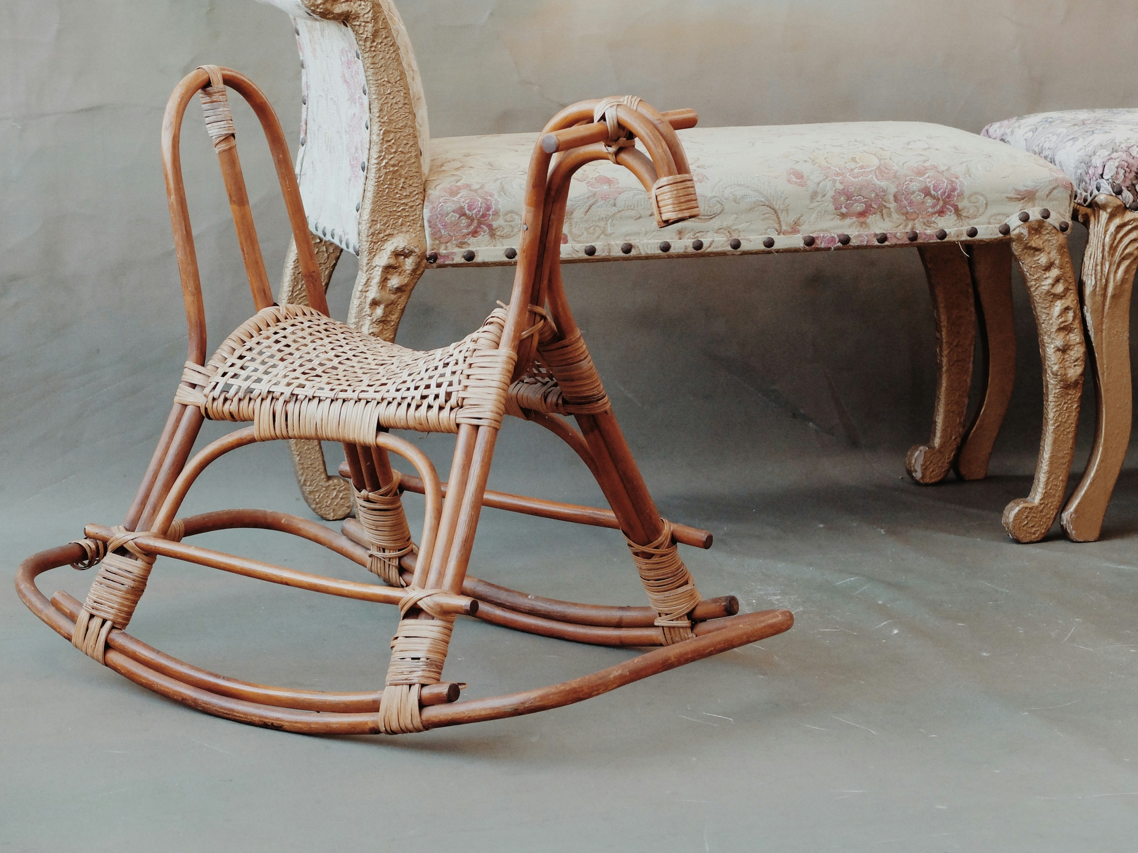 A wooden rocking chair alongside an ornate sofa