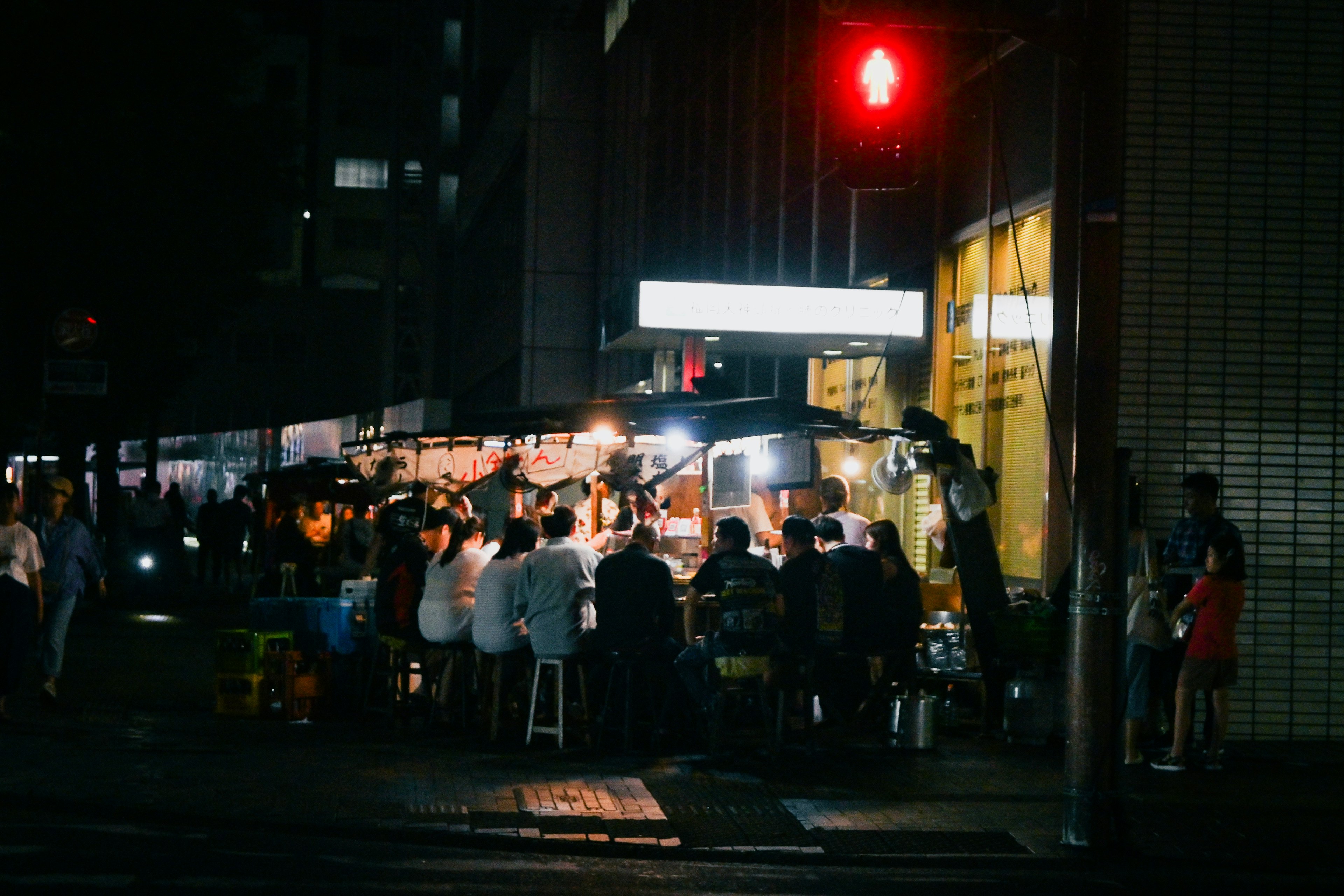 Folla che gusta cibo di strada di notte con un semaforo rosso