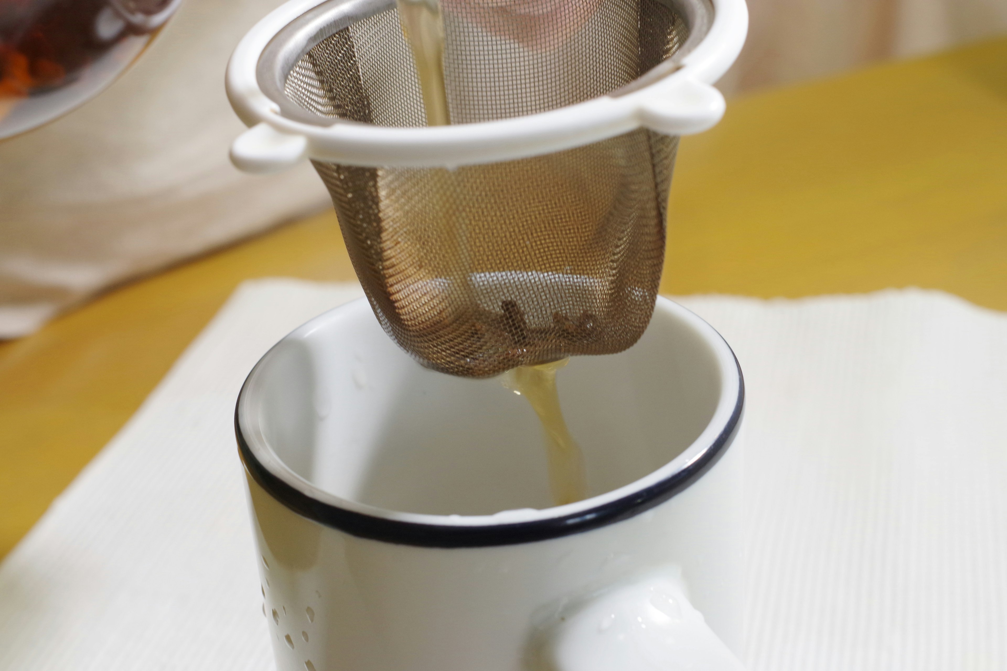 茶こしからお茶がカップに注がれている様子