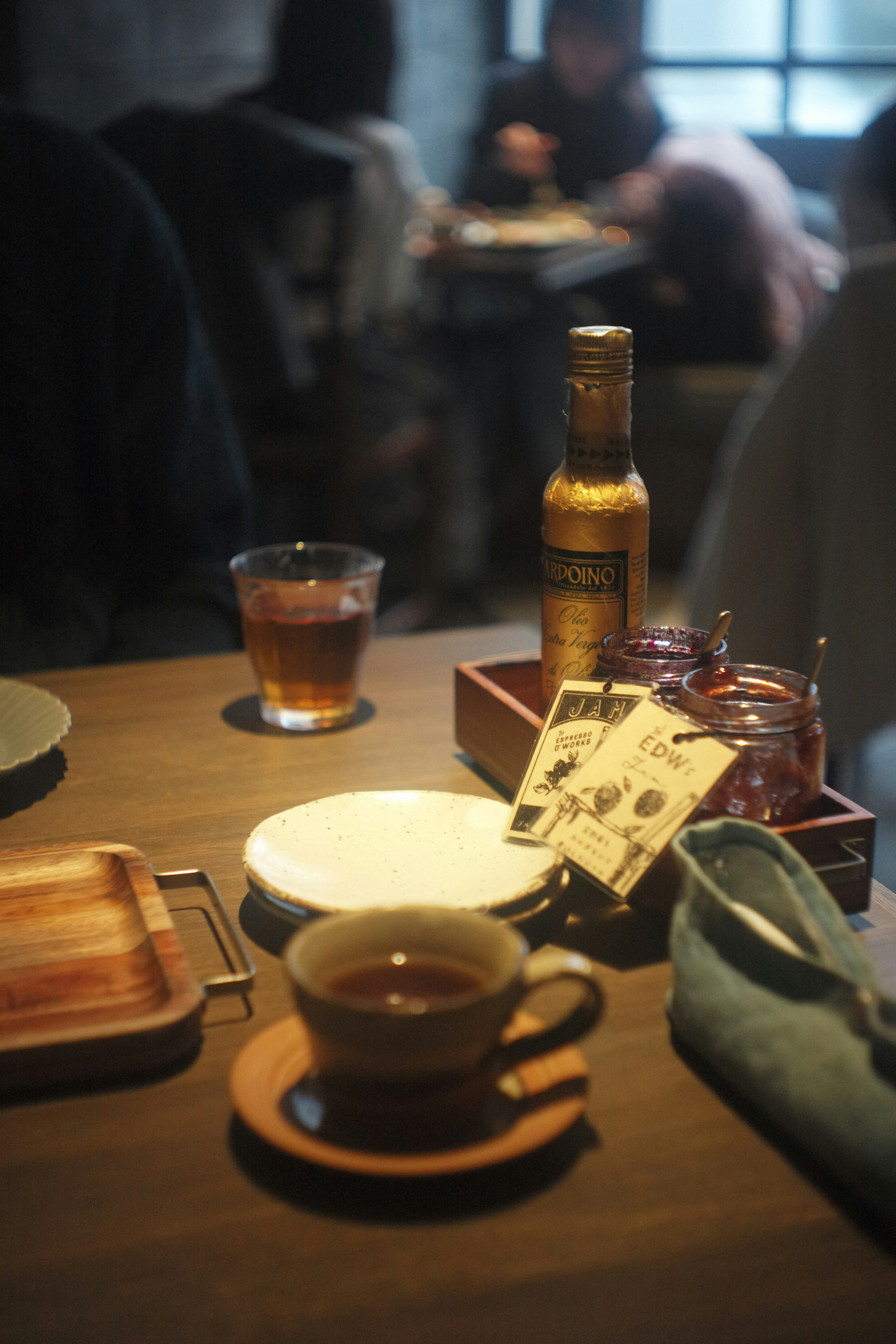 テーブルの上に置かれたコーヒーカップとお茶のグラス 照明が柔らかく落ち着いた雰囲気のカフェ