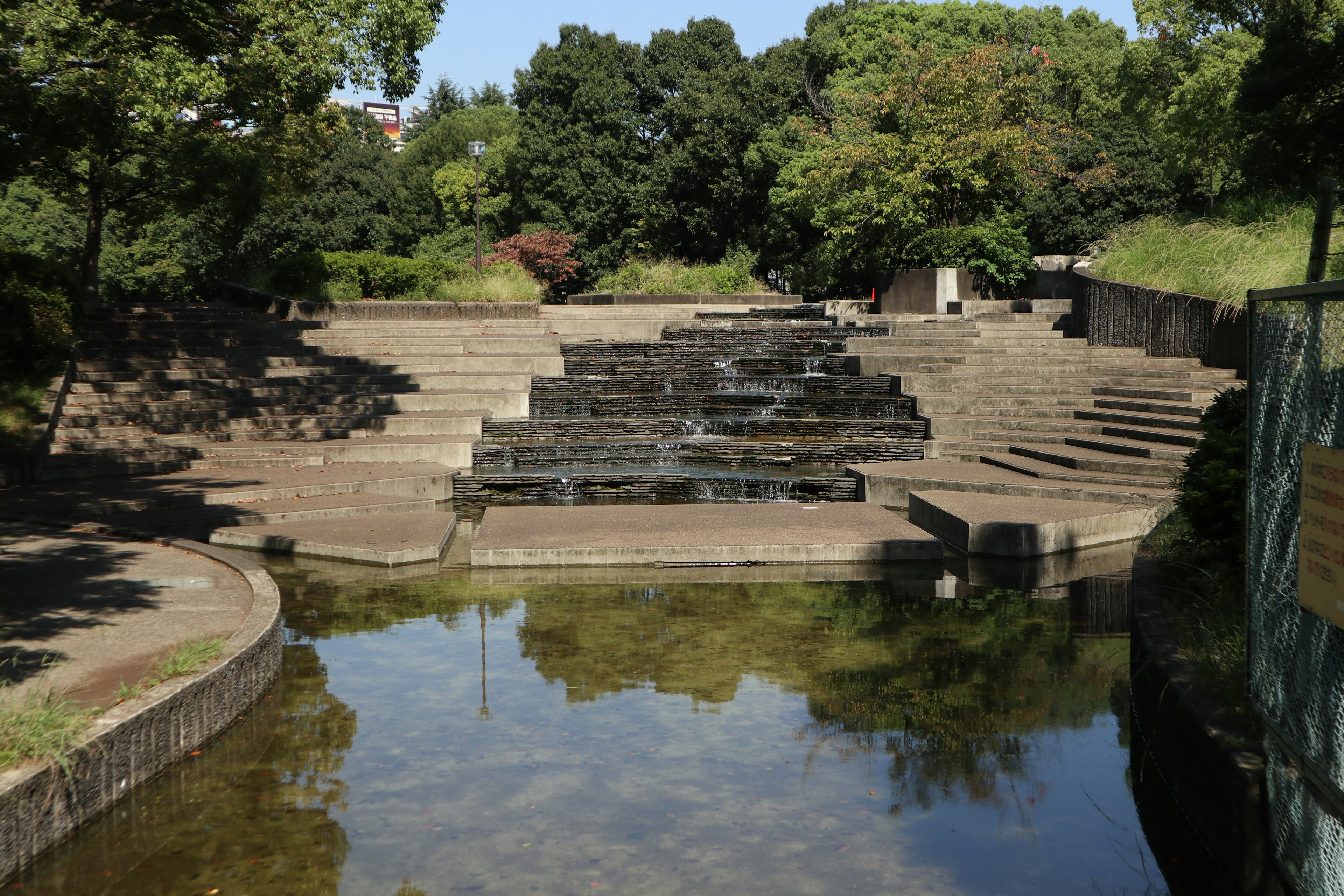 Paysage avec de l'eau qui coule et une structure en pierre en escalier dans un parc