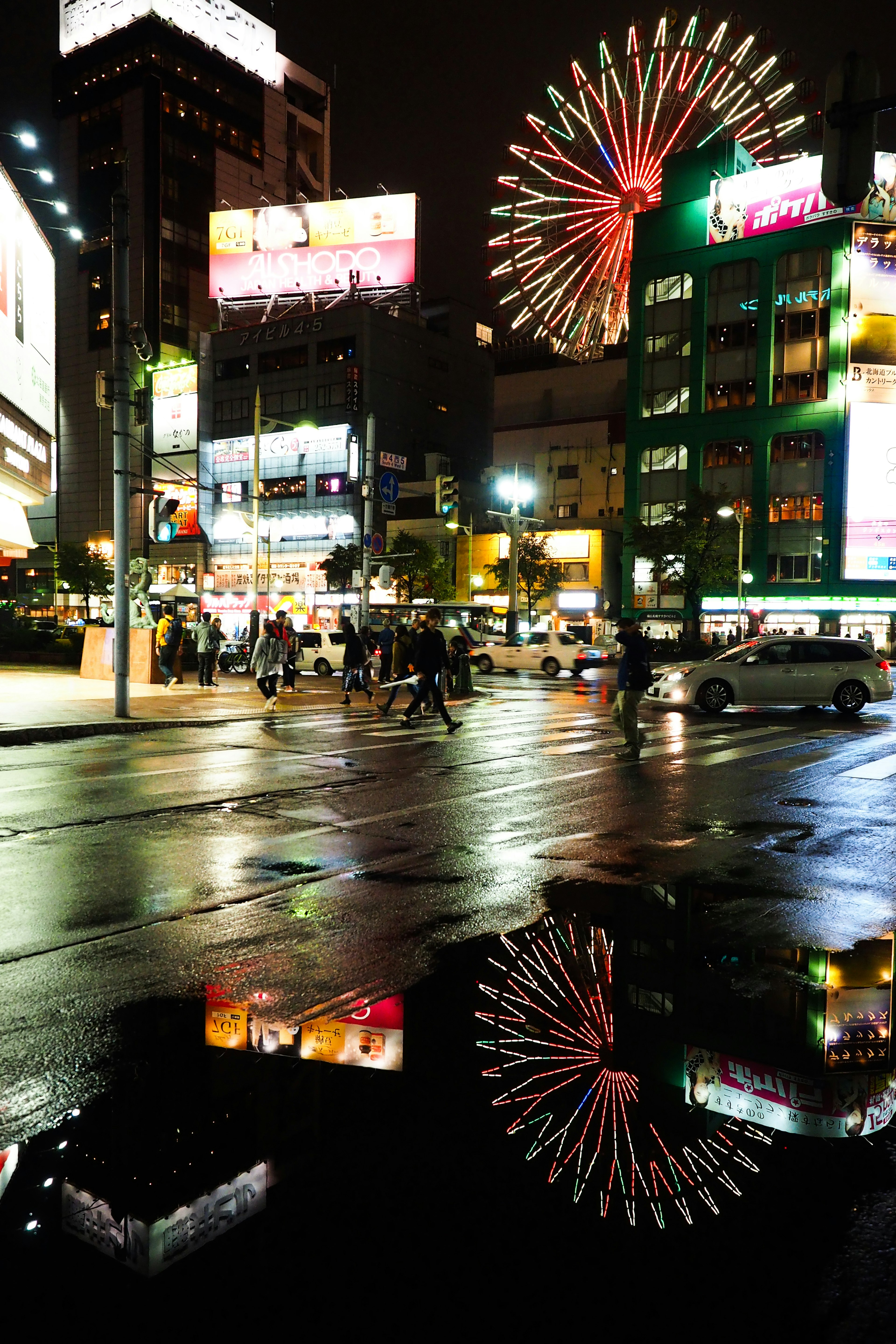 夜の都市風景に映る観覧車の光とネオン