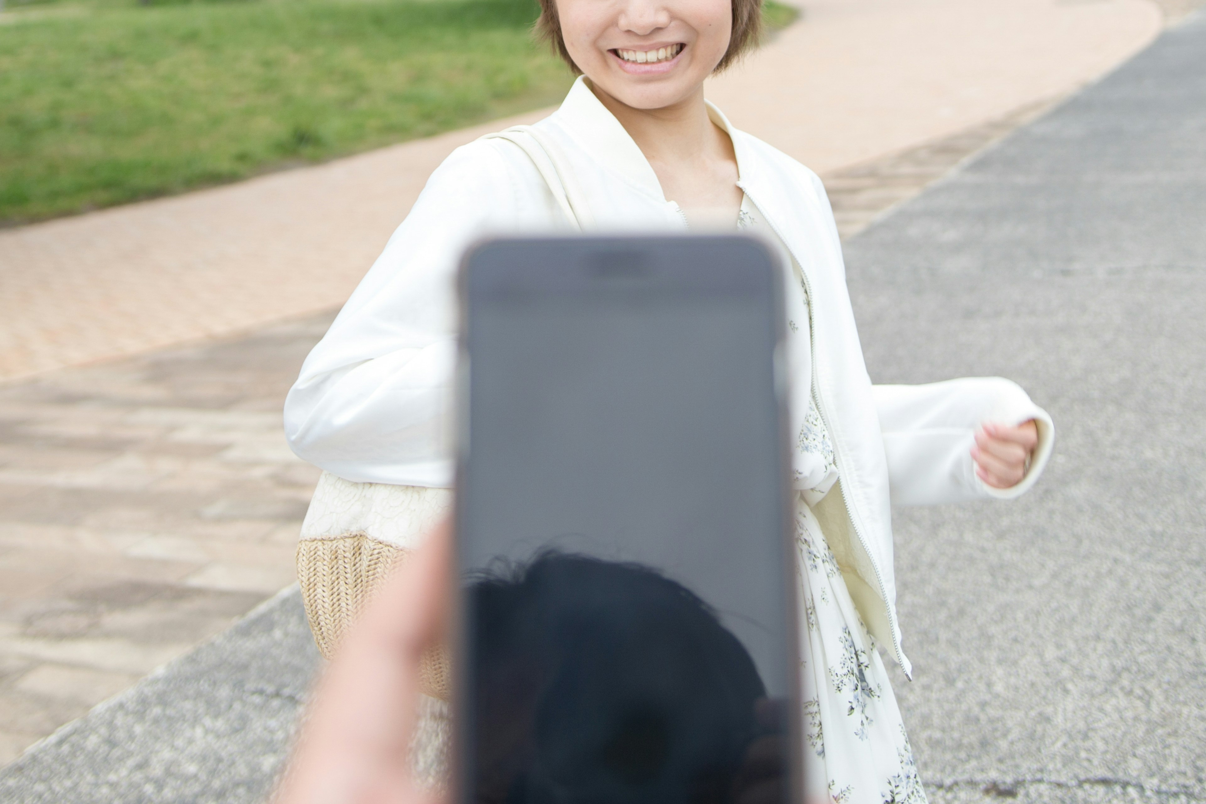 Femme souriante marchant devant une personne tenant un smartphone