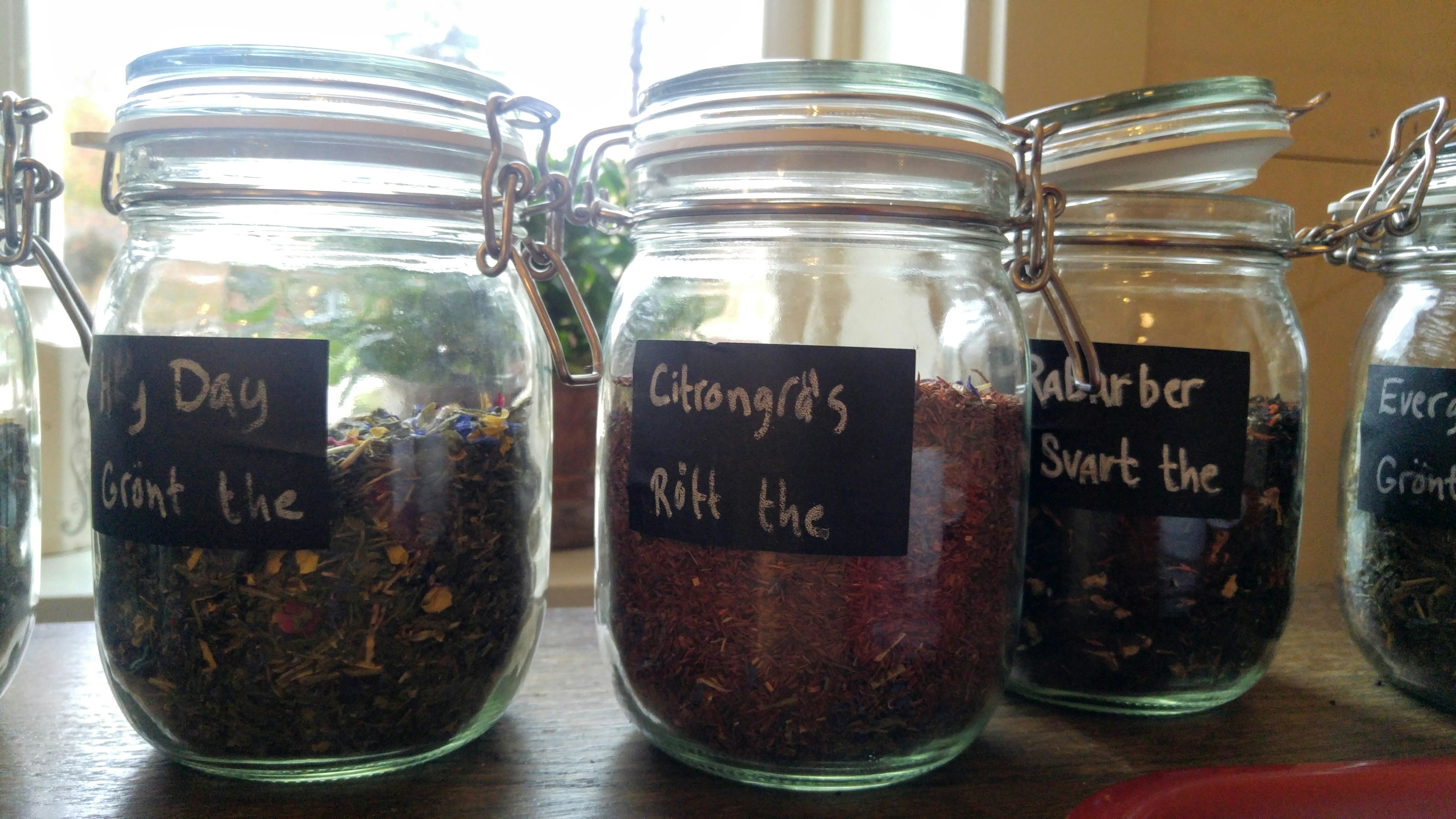 Glass jars filled with various herbs and spice mixes lined up on a wooden surface