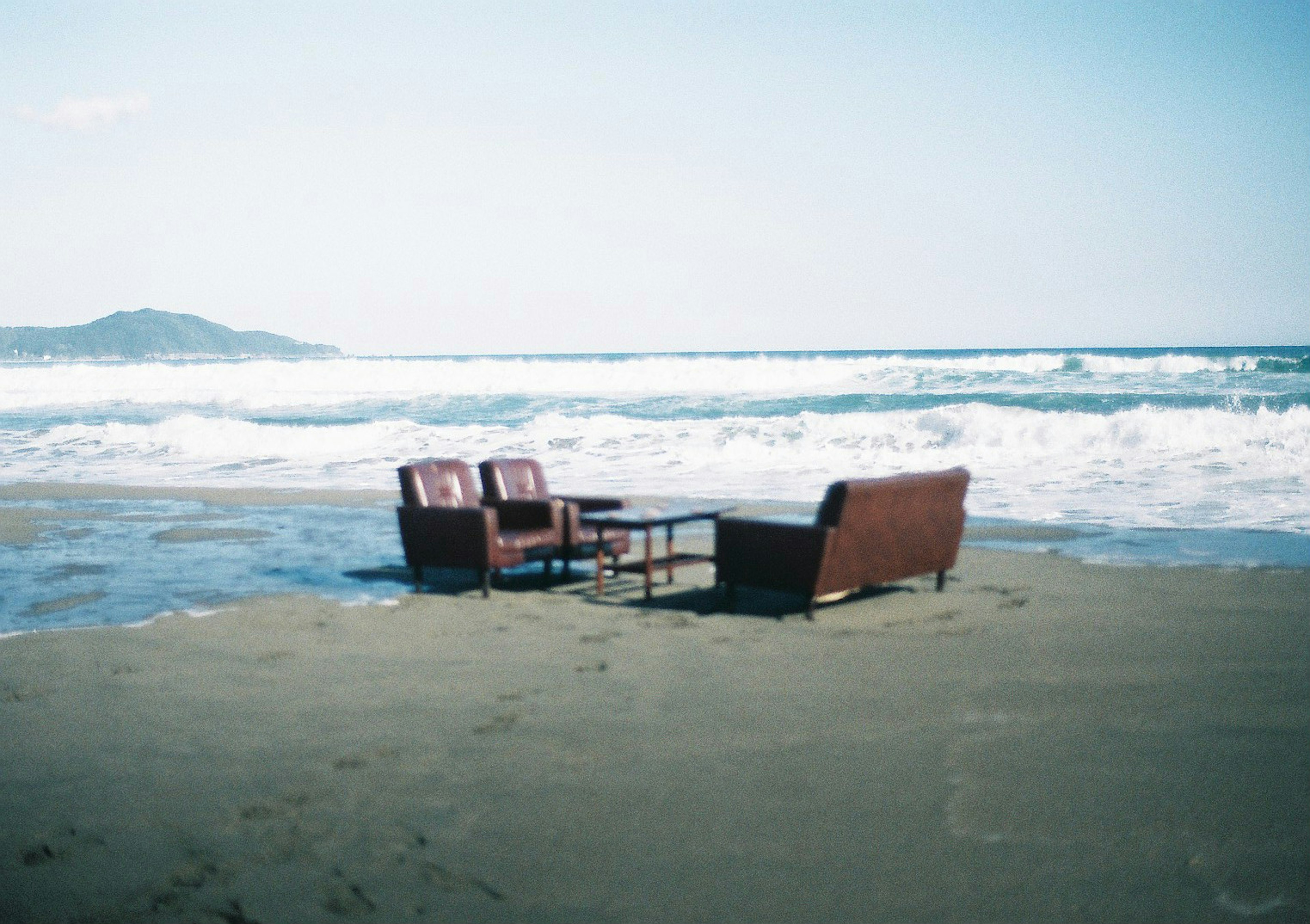 Sofa and table set placed on the beach near the ocean