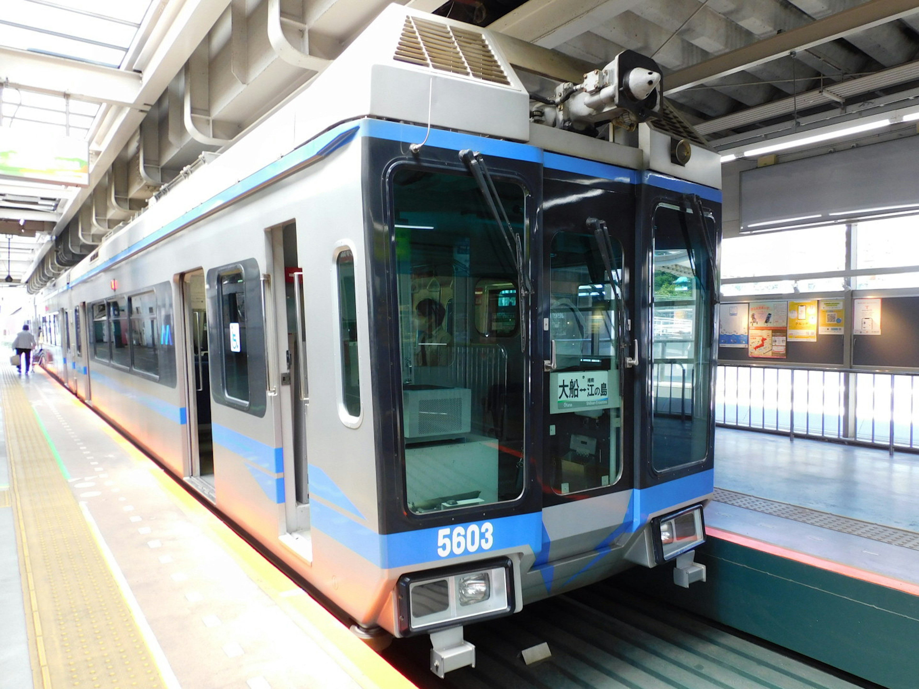 青いラインの入った現代的な電車が駅に停車している様子