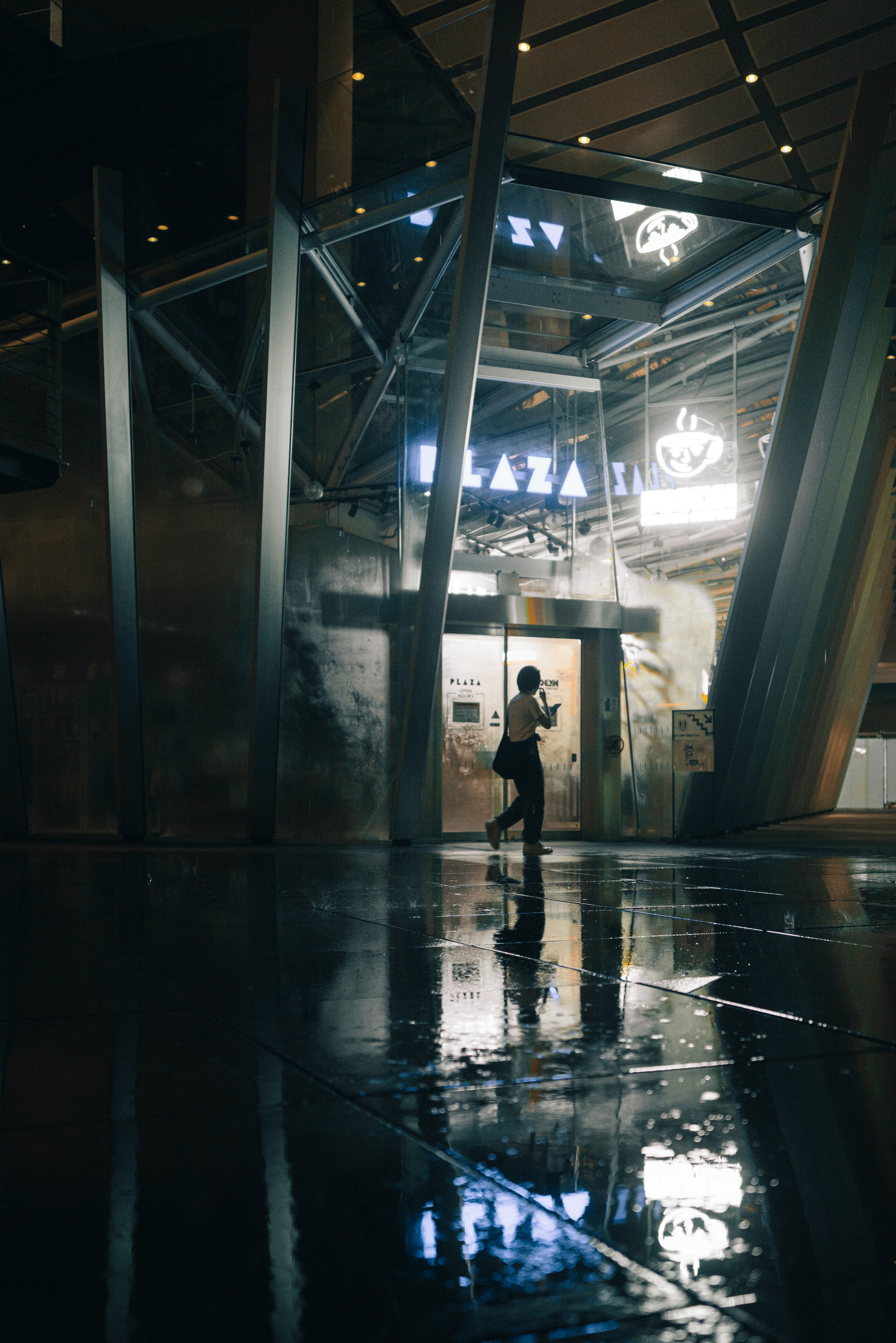 Silhouette of a person standing in a modern building with reflections in puddles