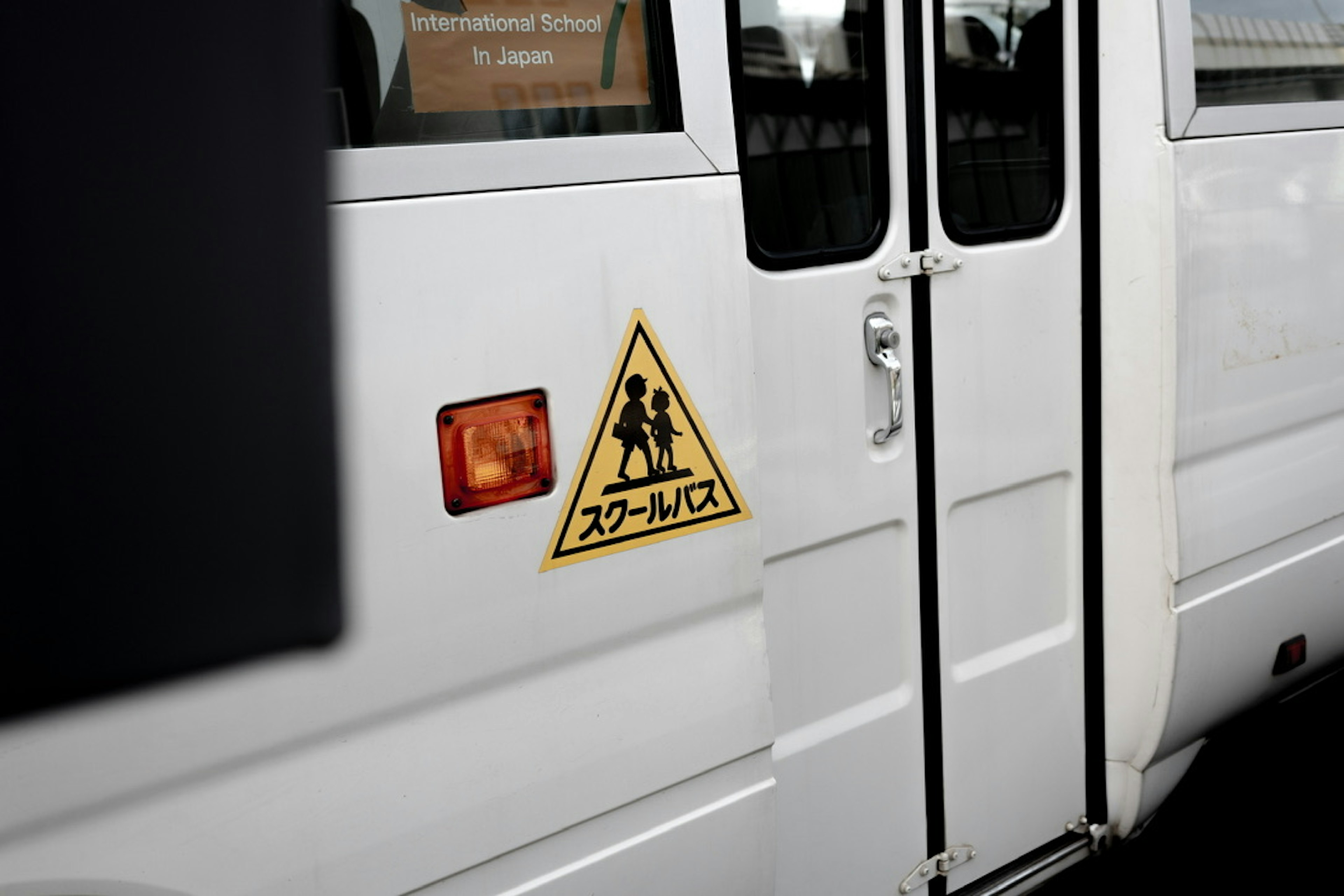 Warning sign for school bus on the side of a white bus