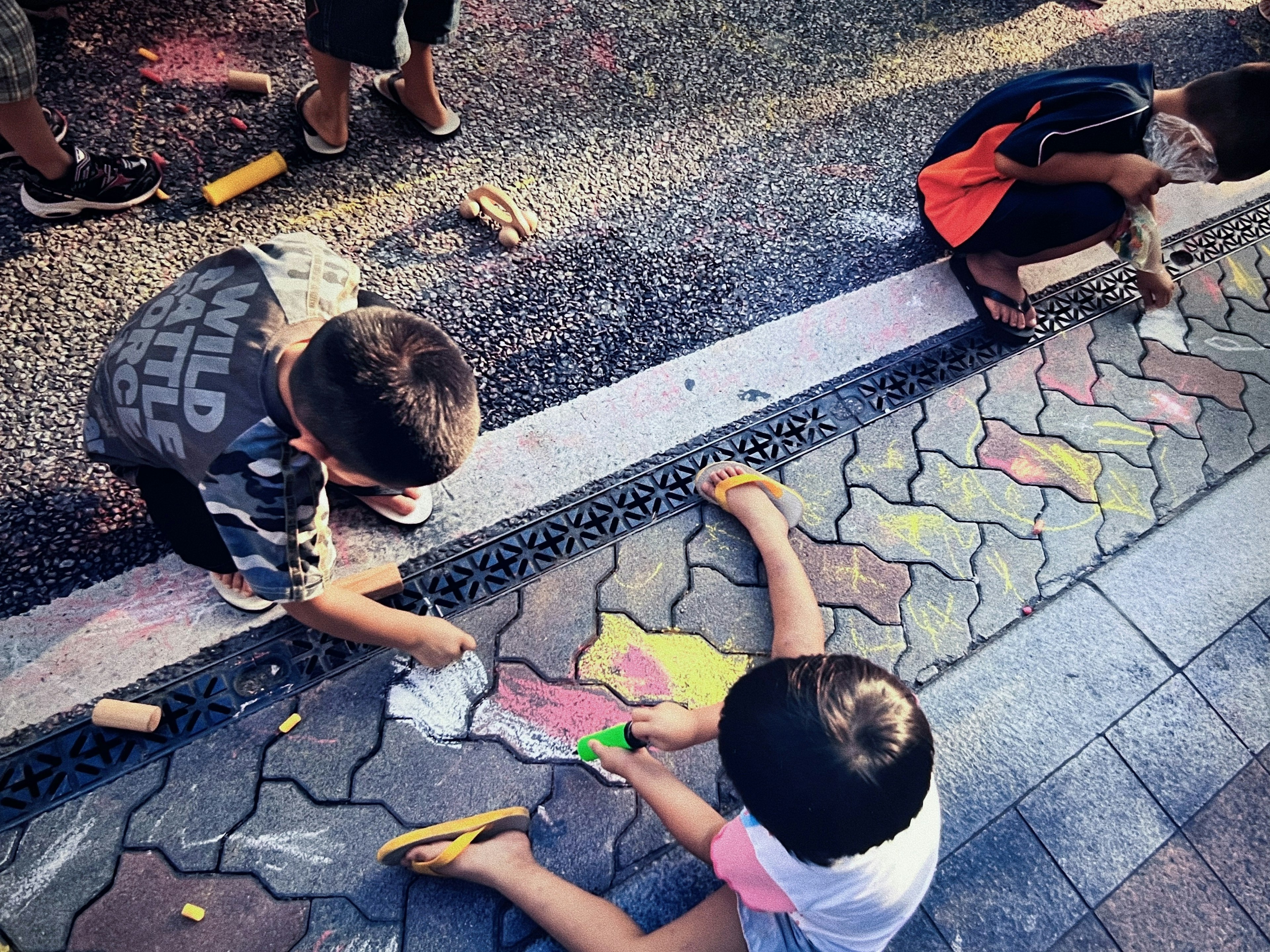 Children drawing colorful chalk art on pavement