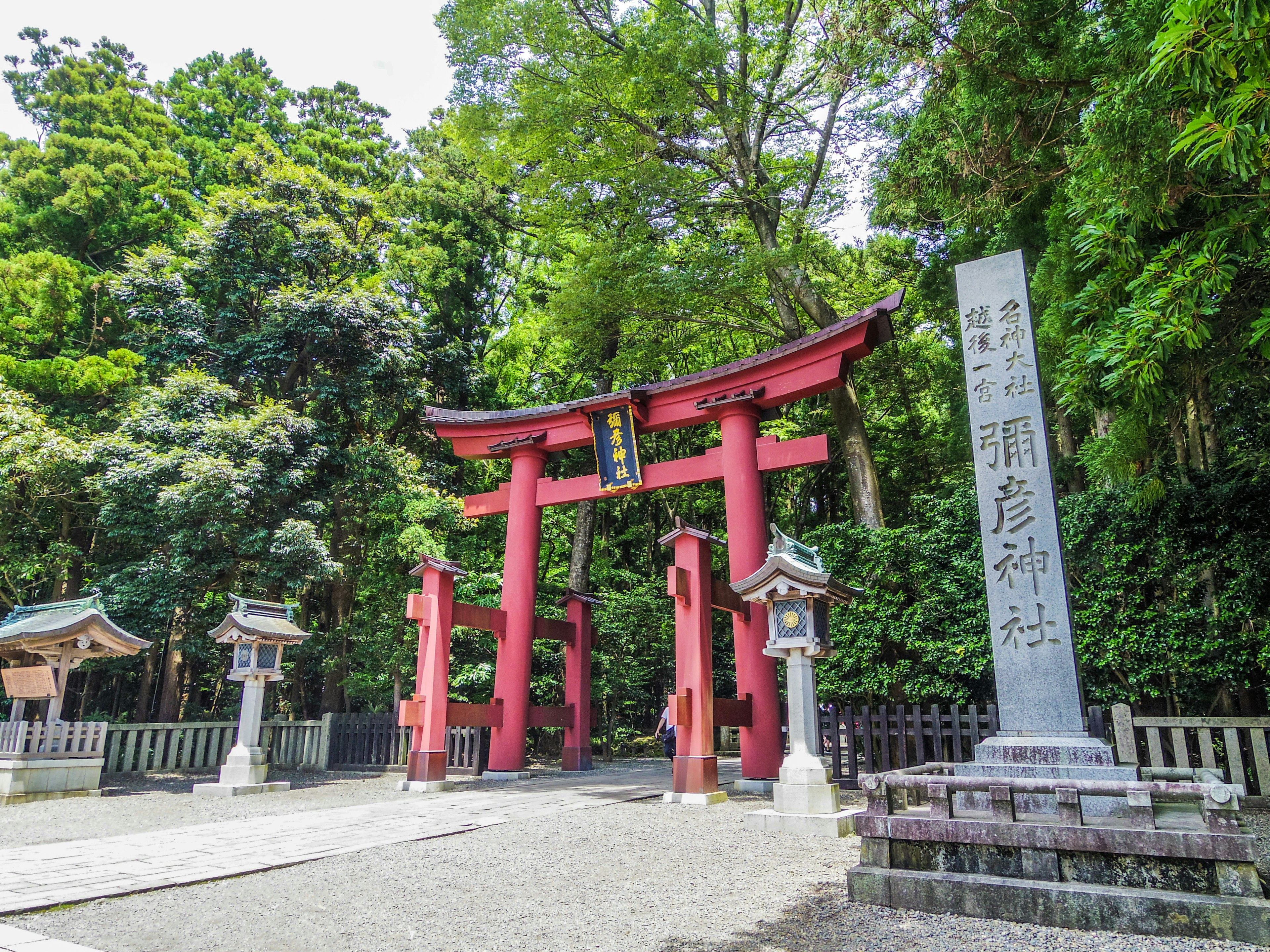 Lối vào đền thờ với cổng torii đỏ và bia đá