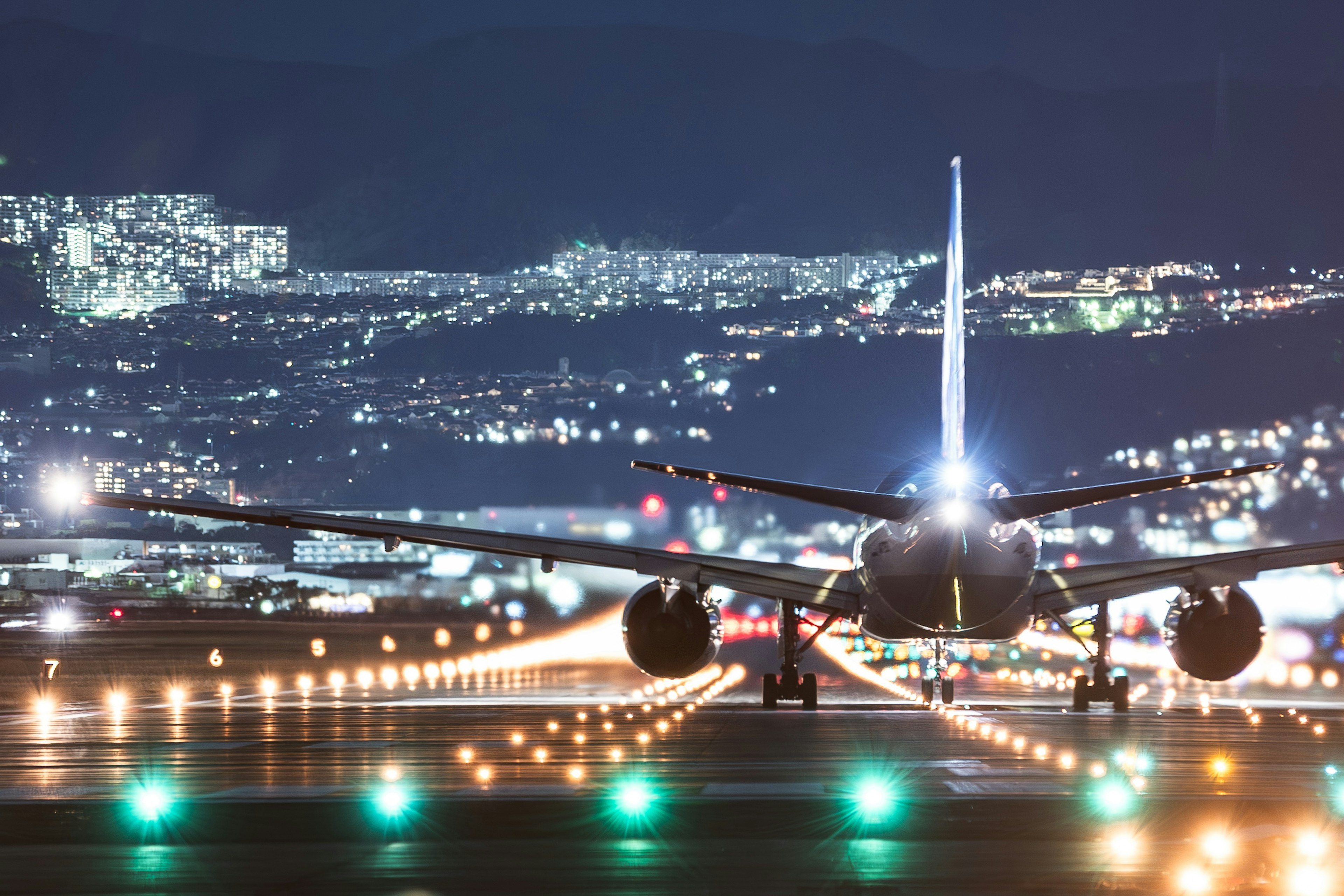 Avion sur la piste de nuit avec des lumières de la ville en arrière-plan