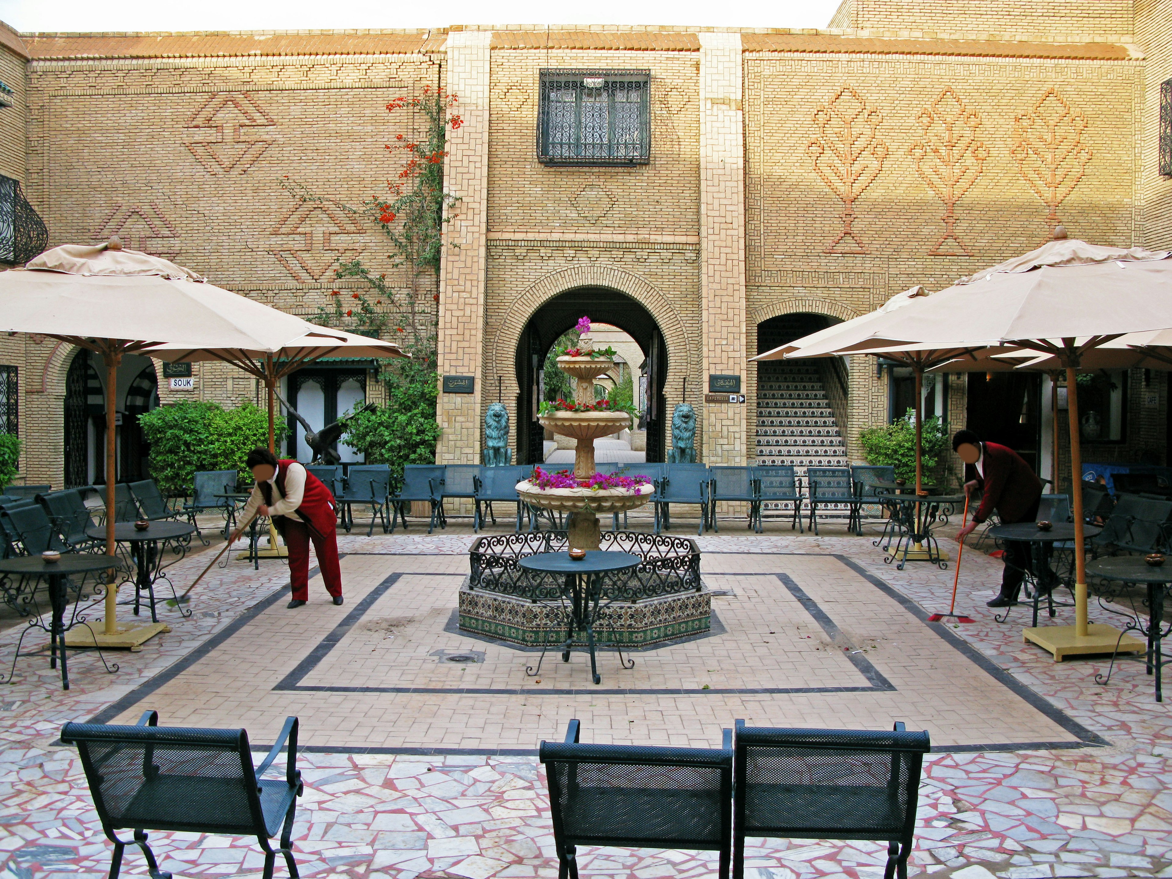 Charmante cour avec une fontaine entourée de chaises et de parasols