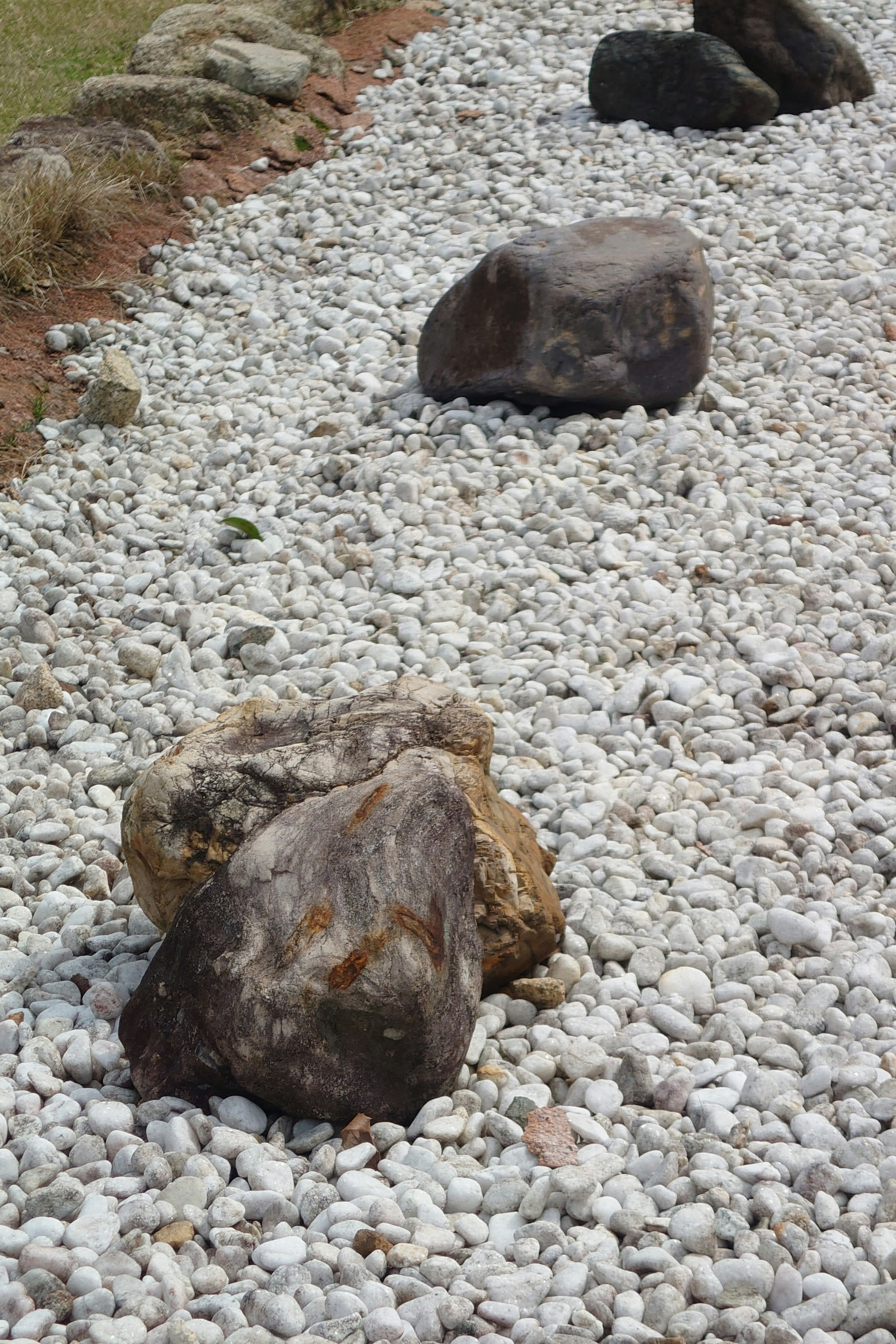 Large rocks placed on a bed of white pebbles in a landscape