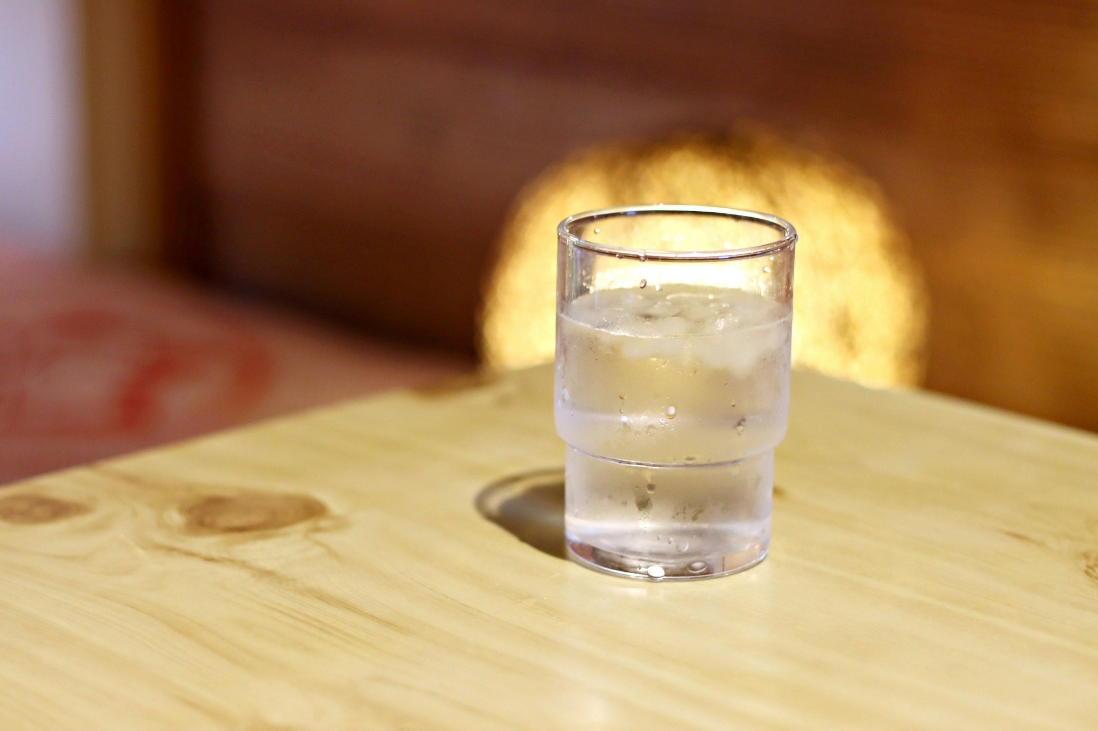 Bicchiere trasparente con acqua e ghiaccio su un tavolo di legno