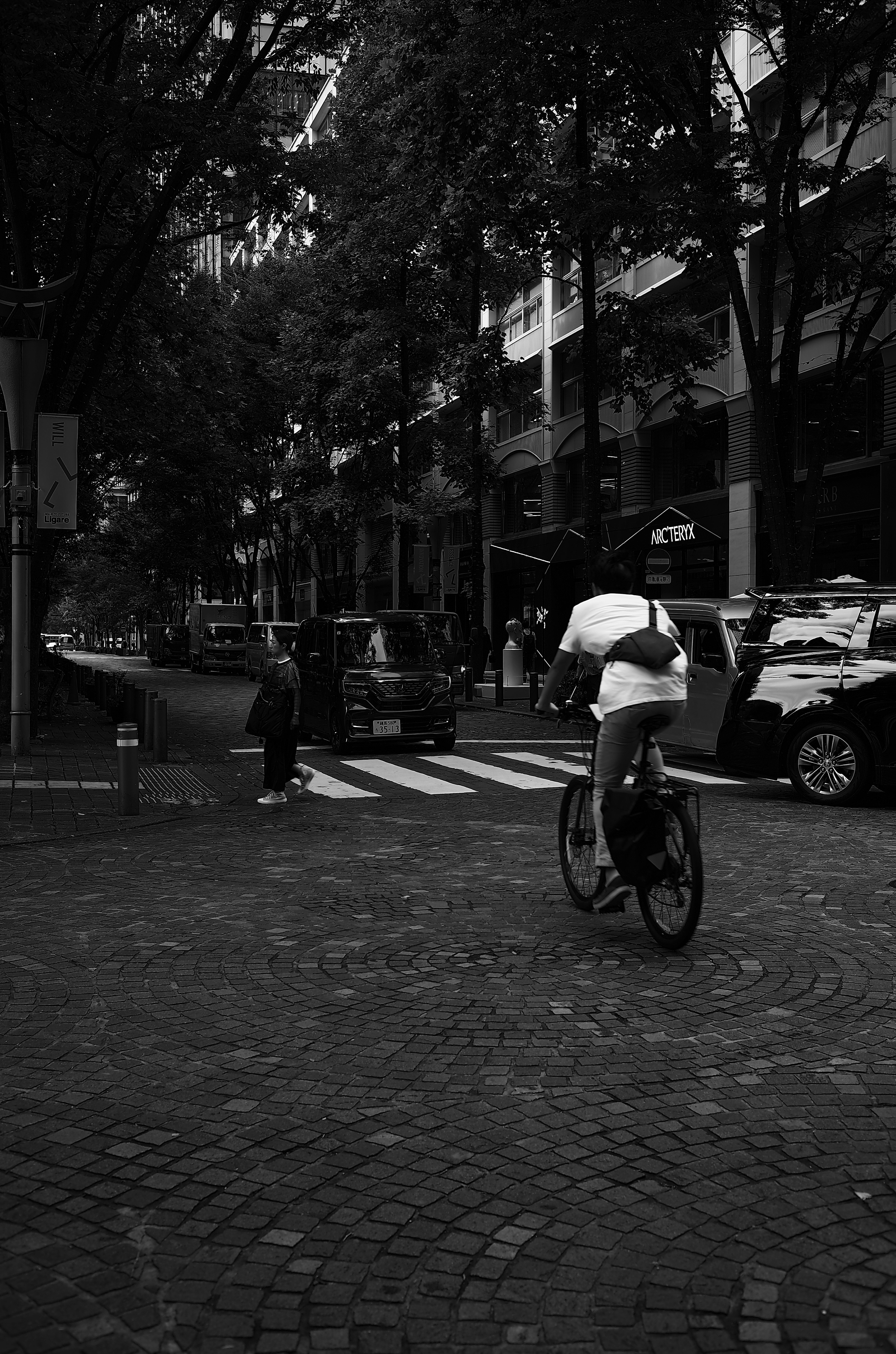 Une personne faisant du vélo à un carrefour urbain en noir et blanc