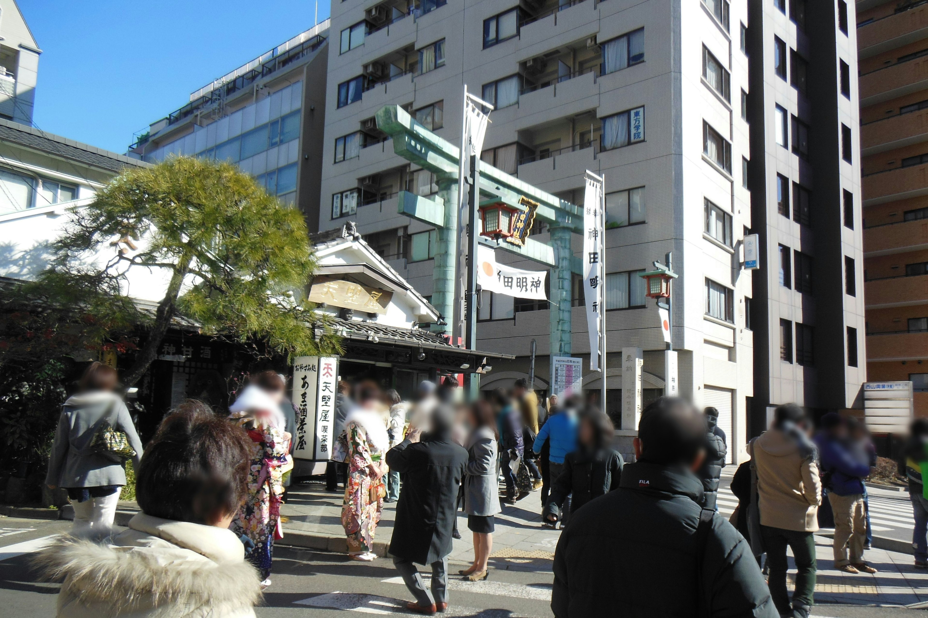 Busy street scene with people walking and traditional shrine entrance