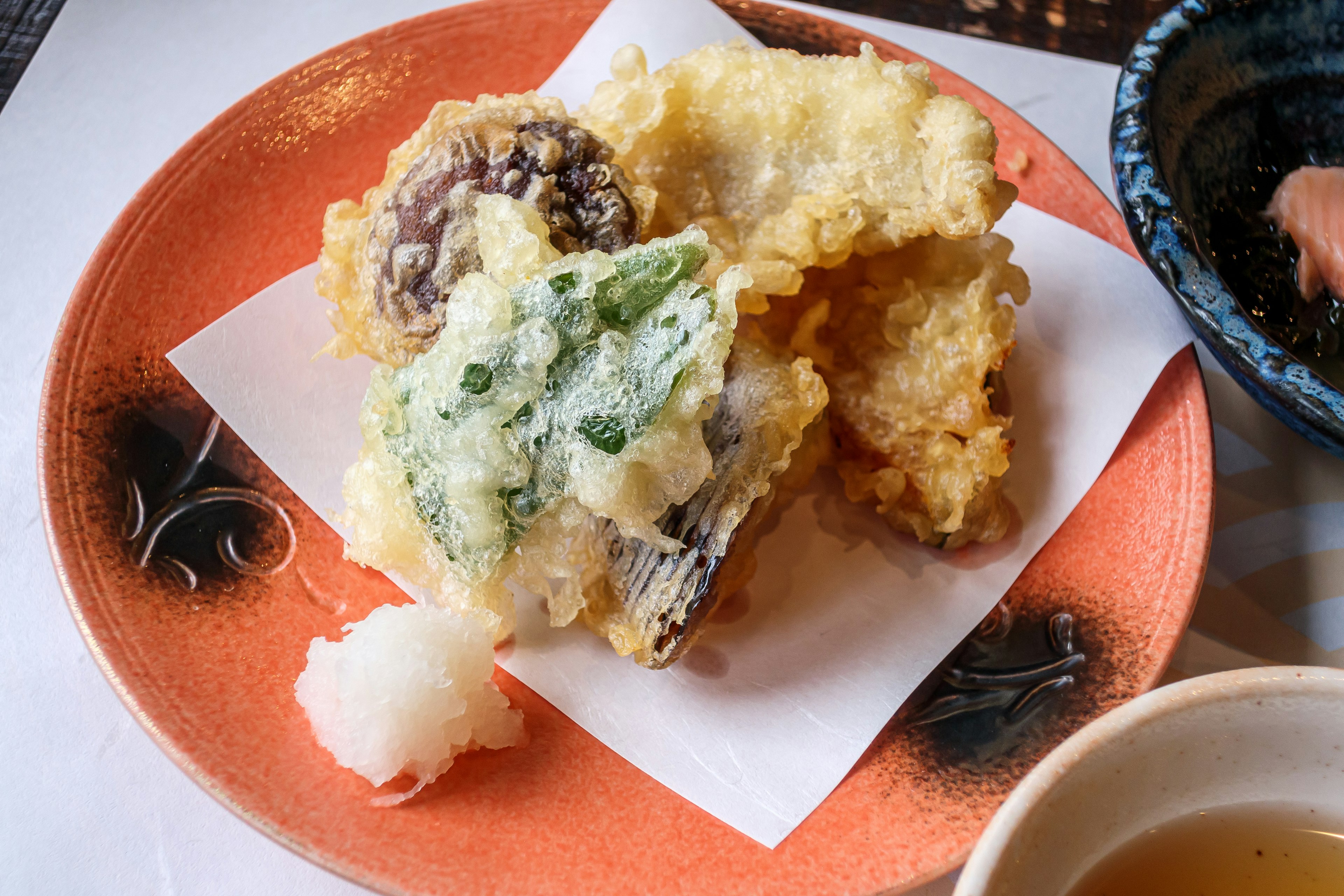 Un assortiment de tempura servi sur une assiette orange