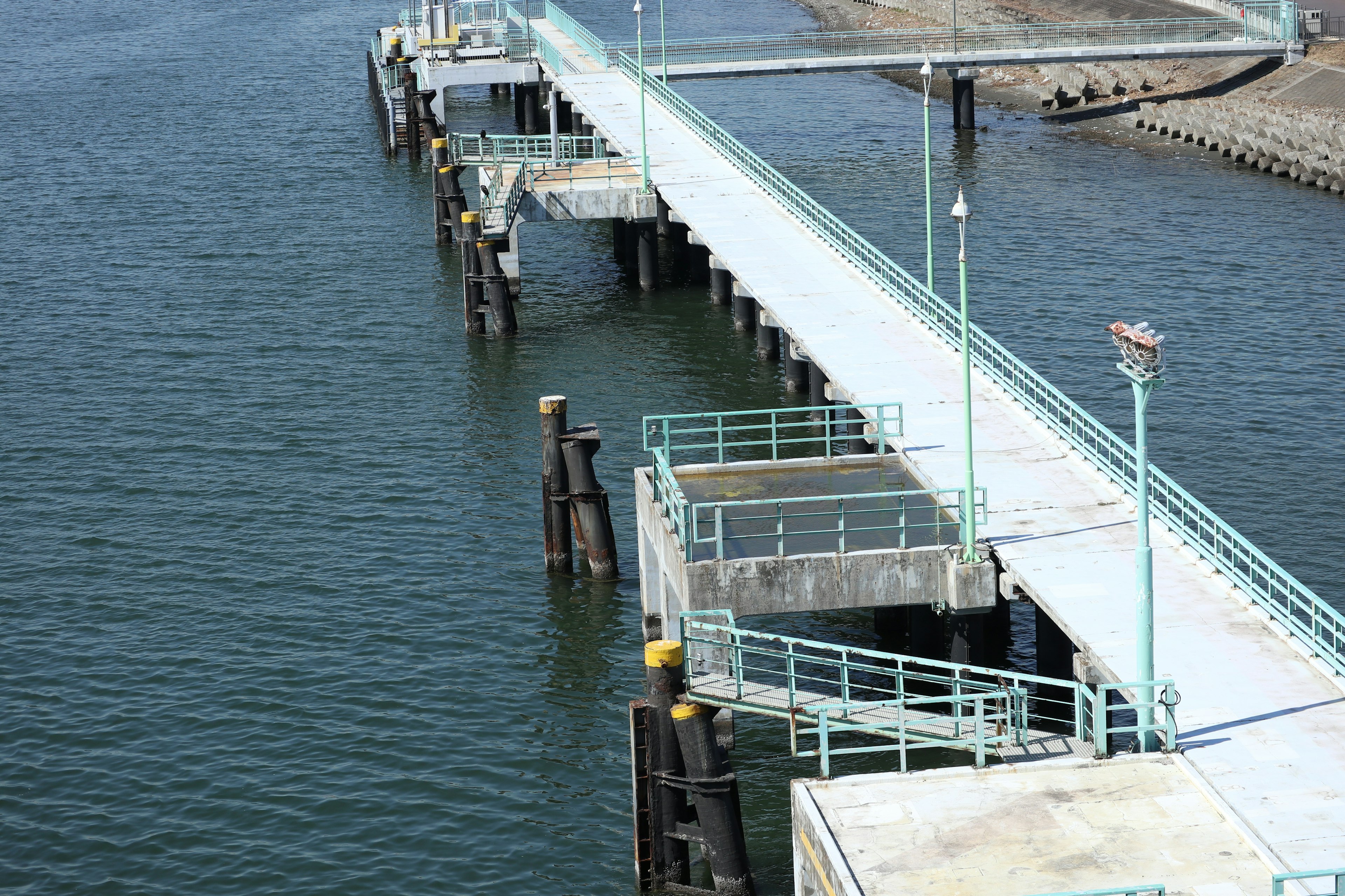 Pier extending over calm water with supporting pillars