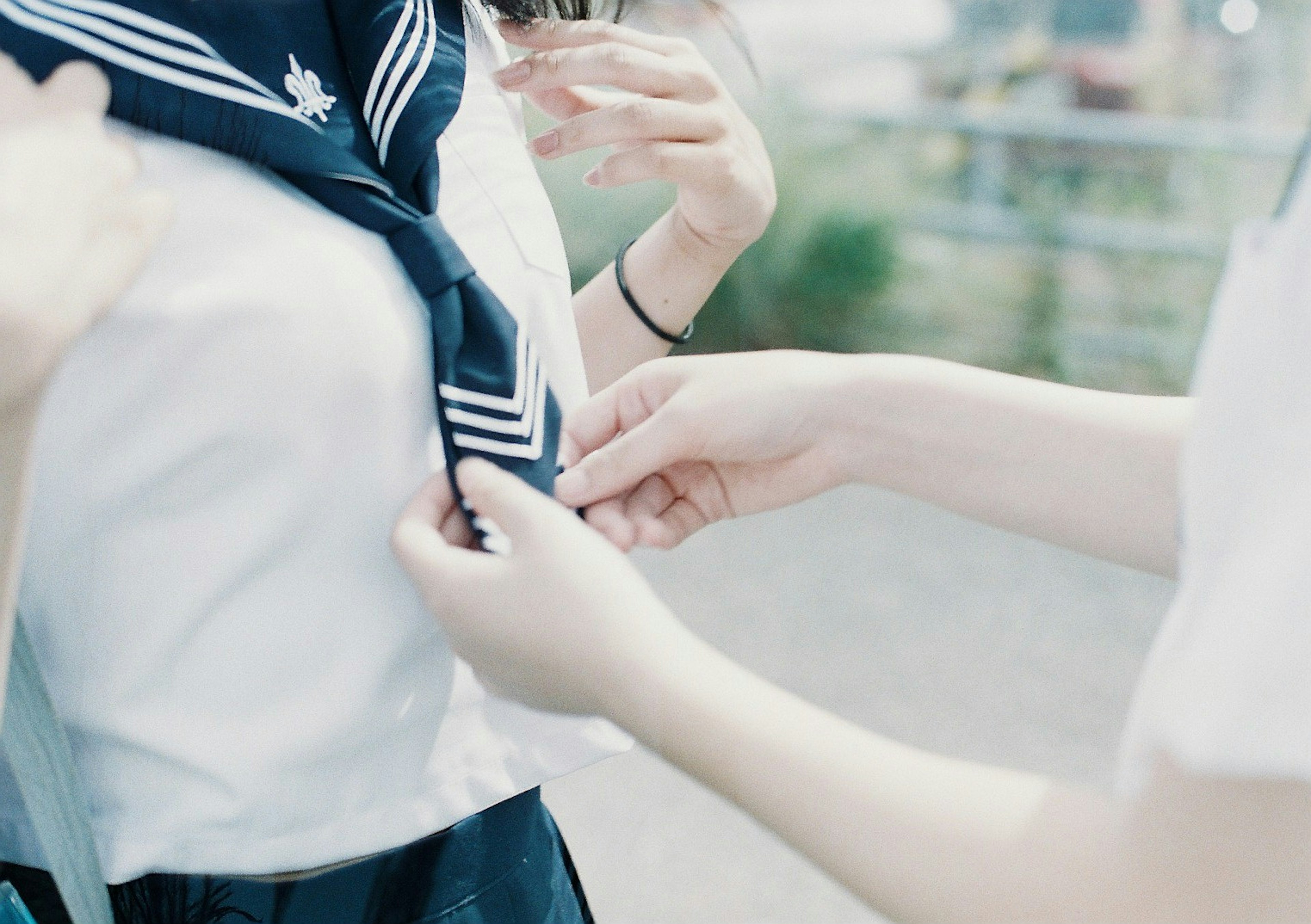 Two students adjusting a sailor collar on a school uniform