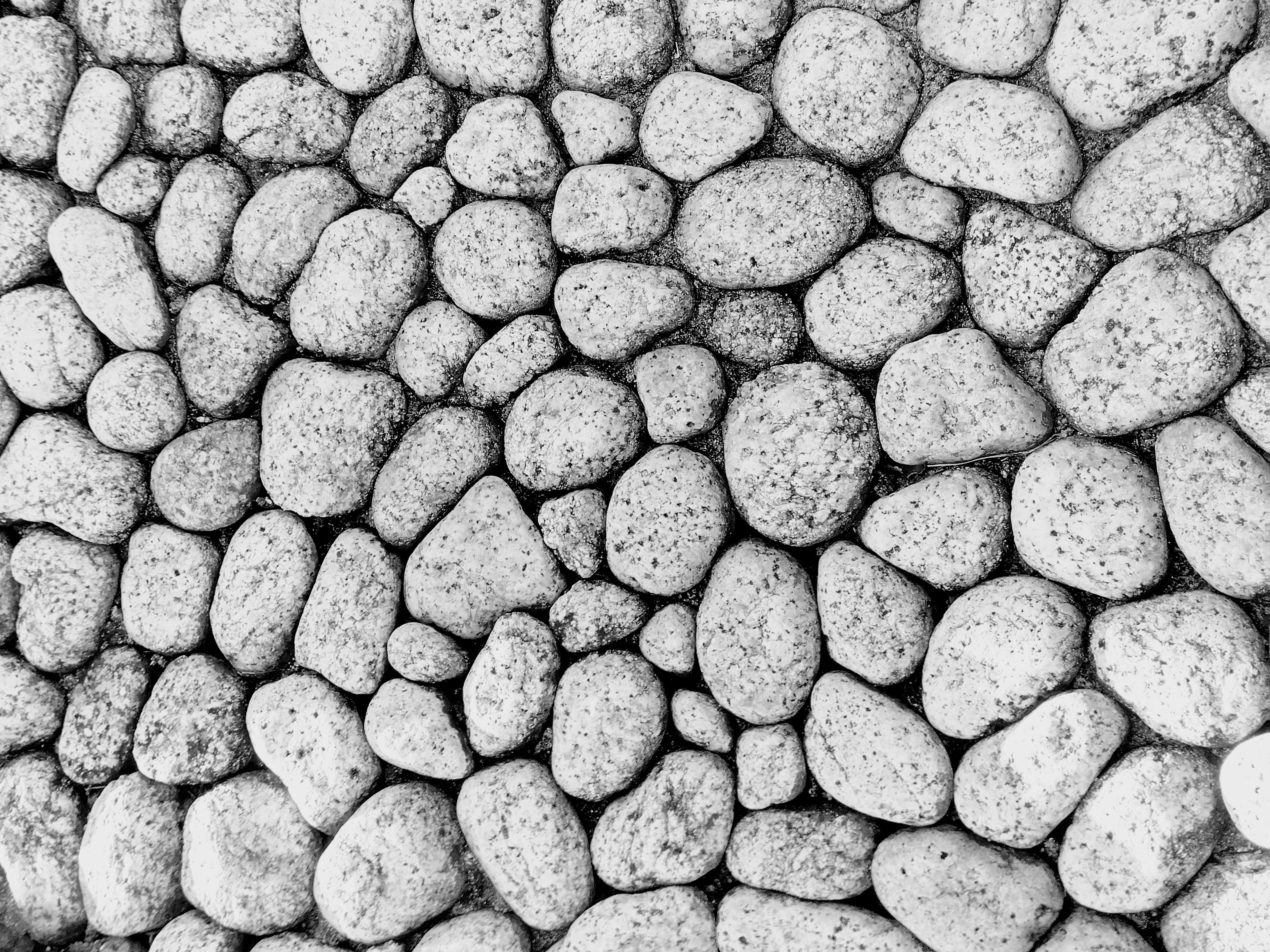 Textured pattern of randomly arranged pebbles in black and white