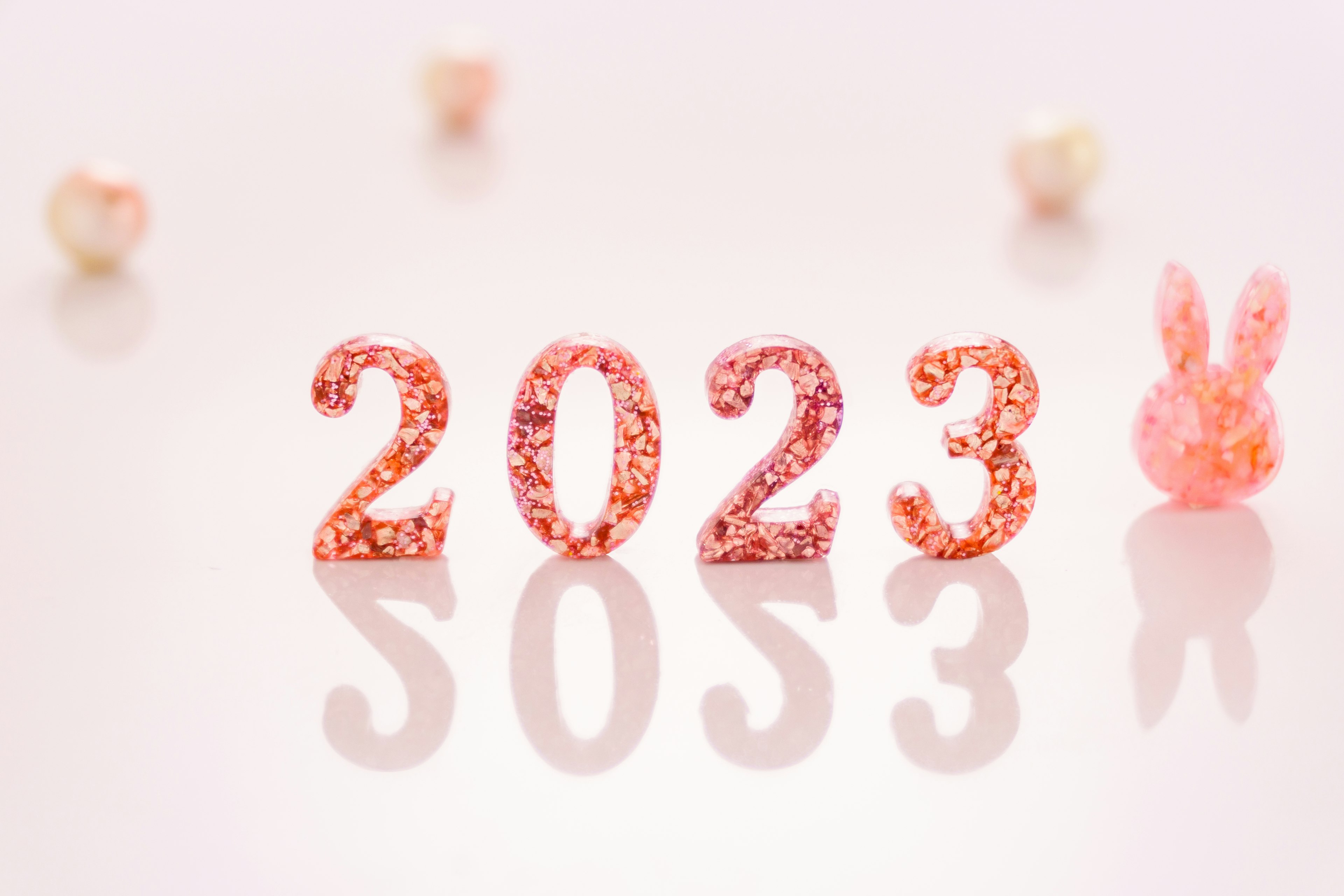 반짝이는 분홍색 숫자로 쓰인 2023년과 귀여운 토끼 장식