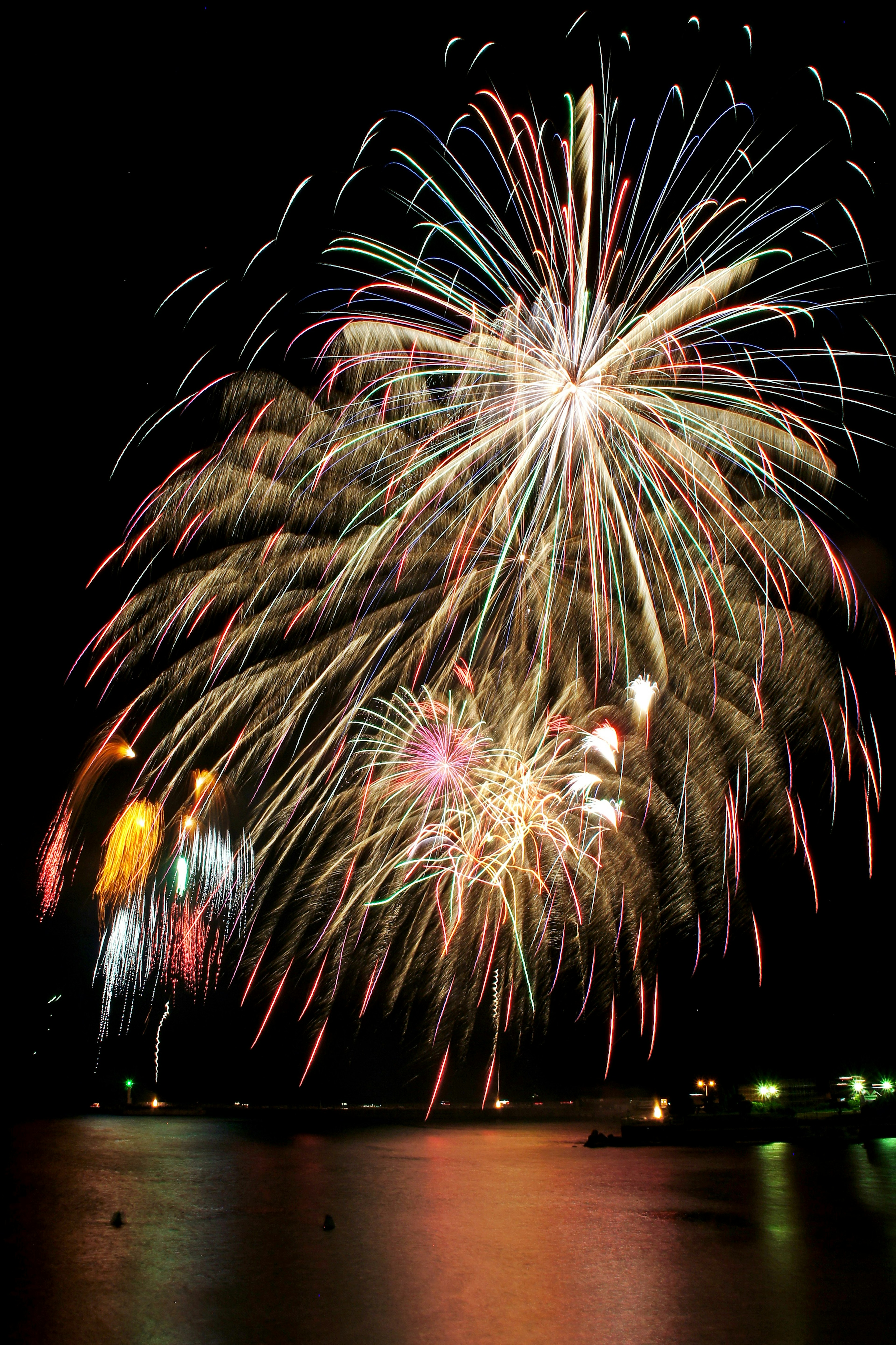 Des feux d'artifice colorés éclatent dans le ciel nocturne se reflétant sur le lac