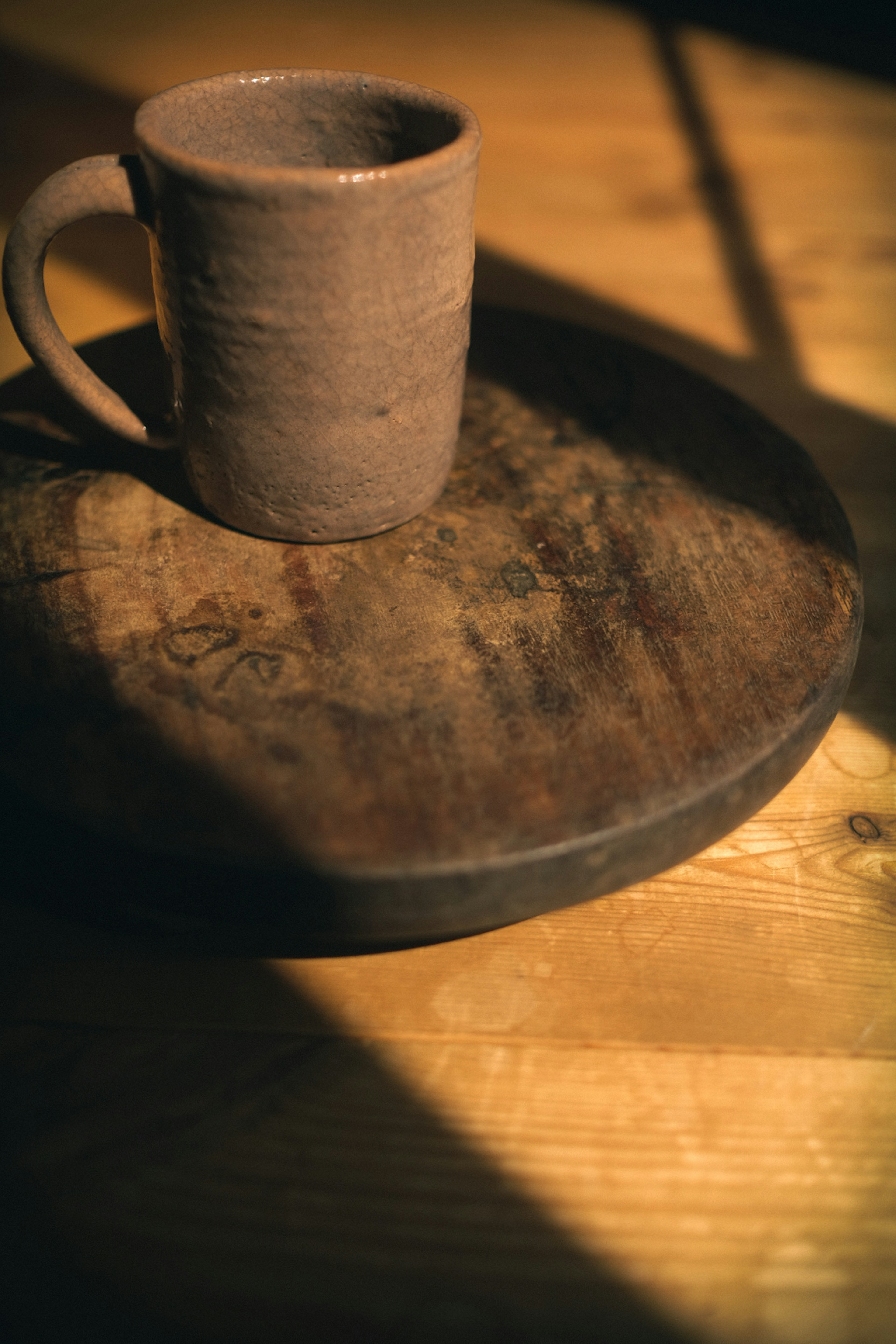 Tasse en céramique sur un plateau en bois avec lumière chaude et texture de table en bois