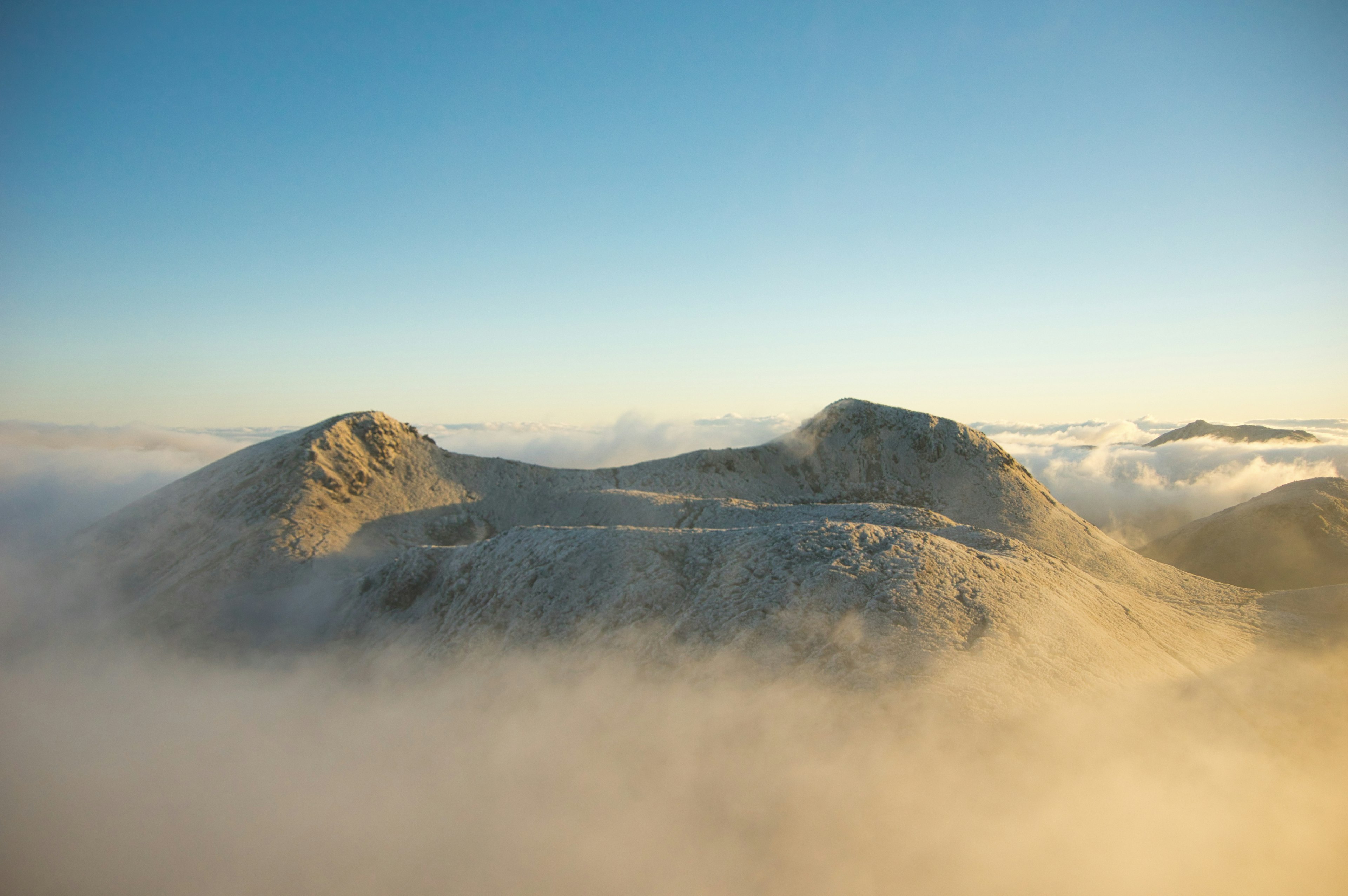 Paisaje montañoso envuelto en niebla con cielo azul claro