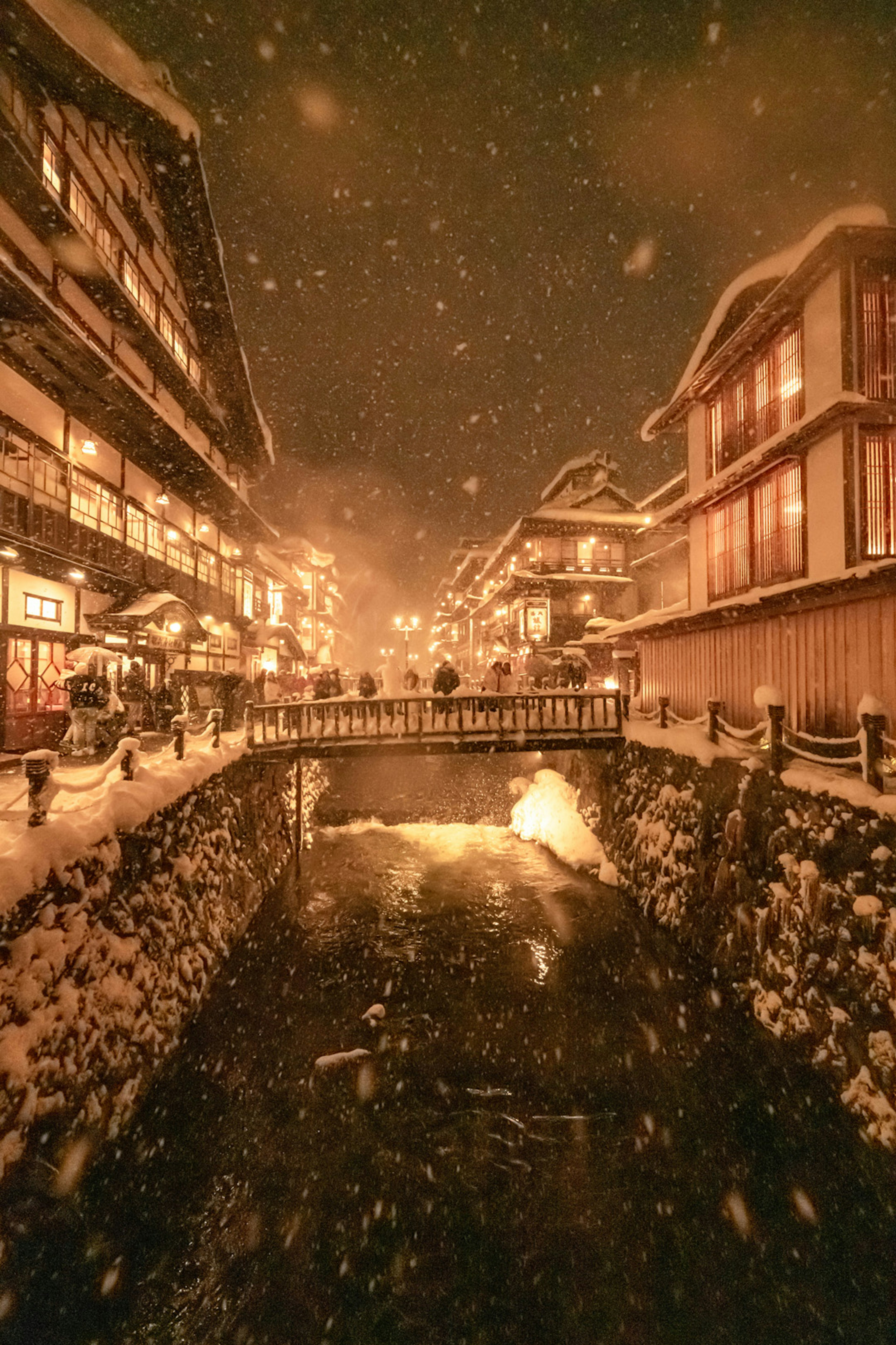 Scène de rue enneigée avec une rivière Lumières chaudes illuminant des bâtiments