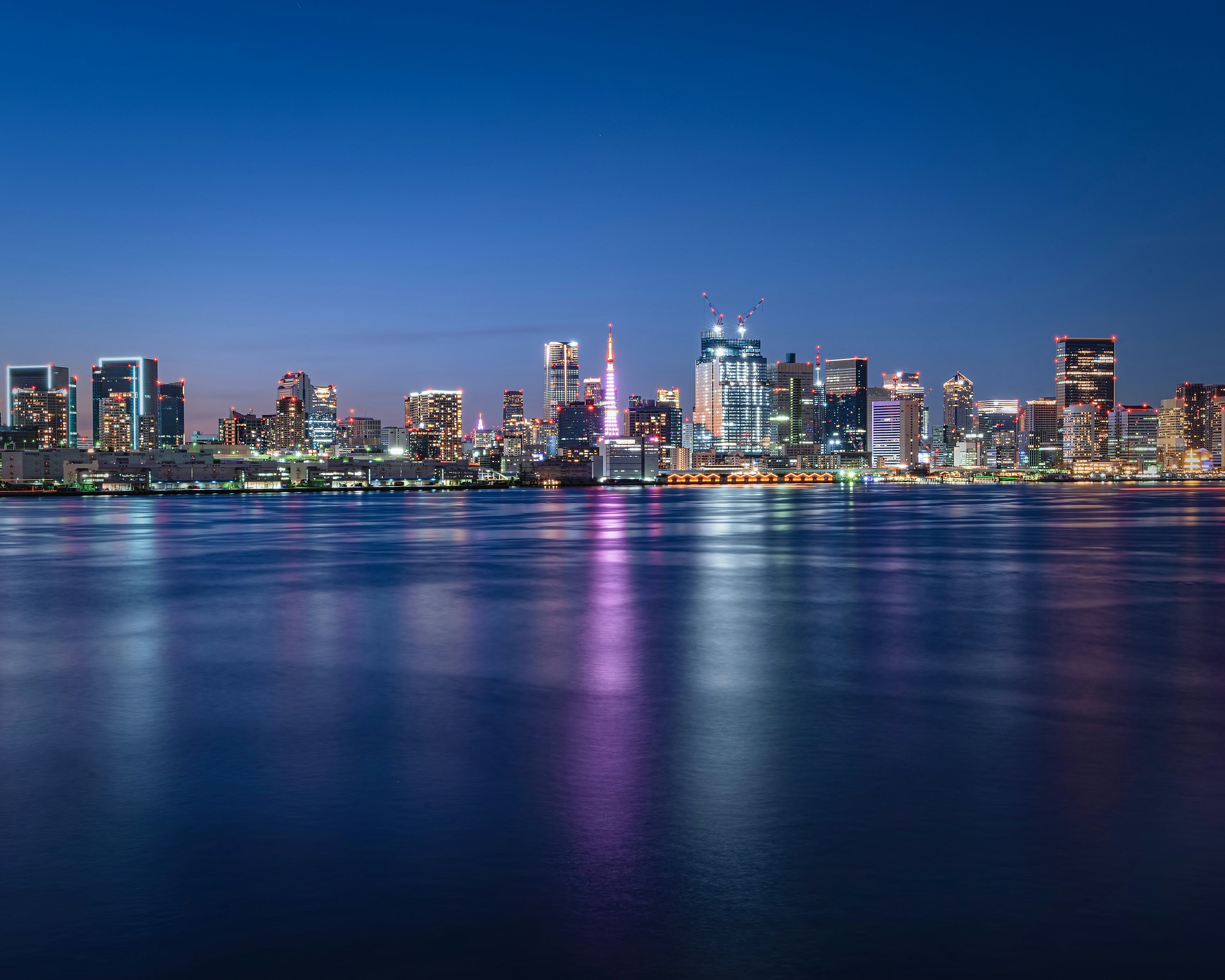 夜景の都市のスカイラインと水面の反射