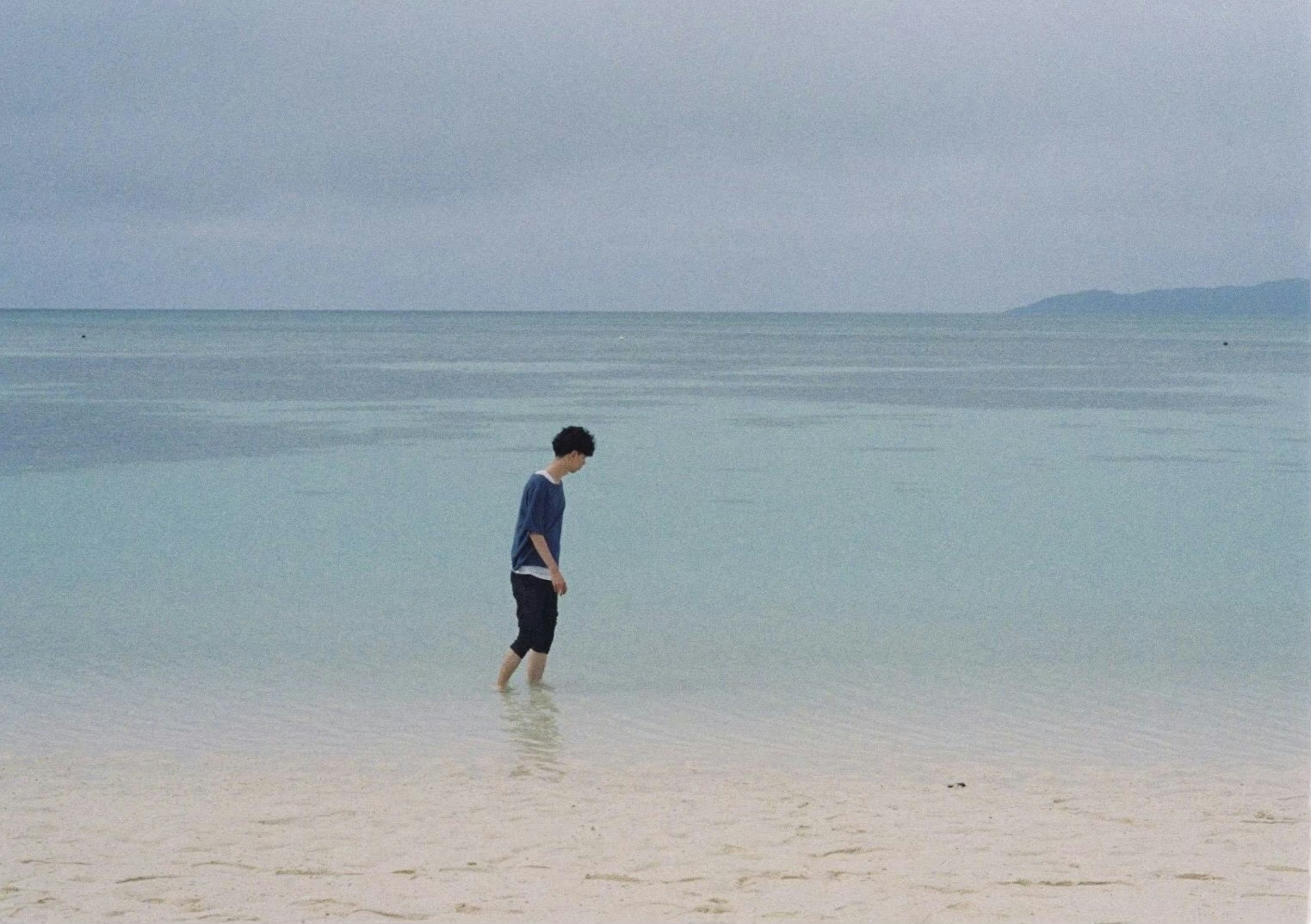 Silhouette of a boy walking on the beach with calm water