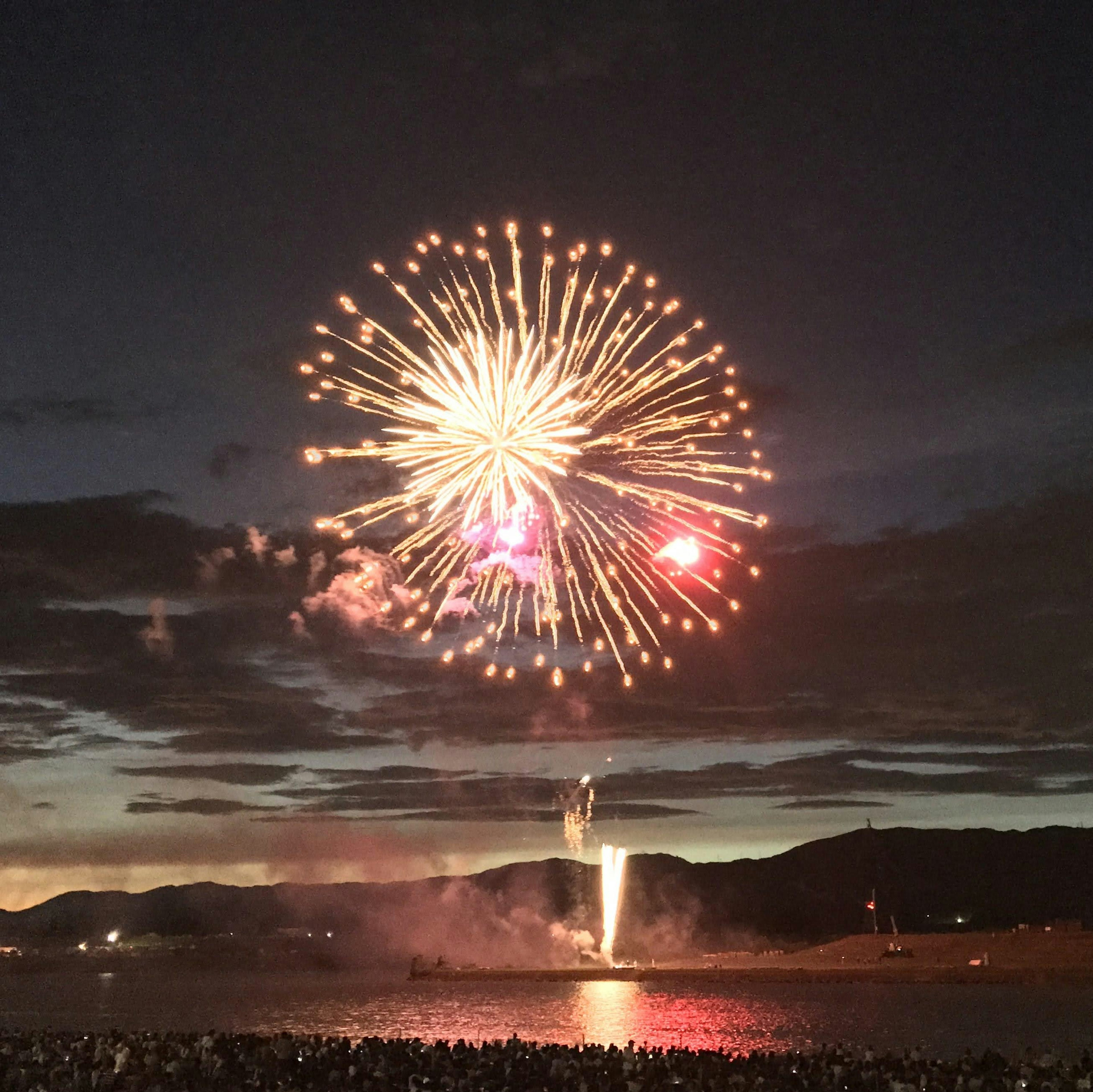 Espectáculo de fuegos artificiales coloridos iluminando el cielo nocturno con espectadores