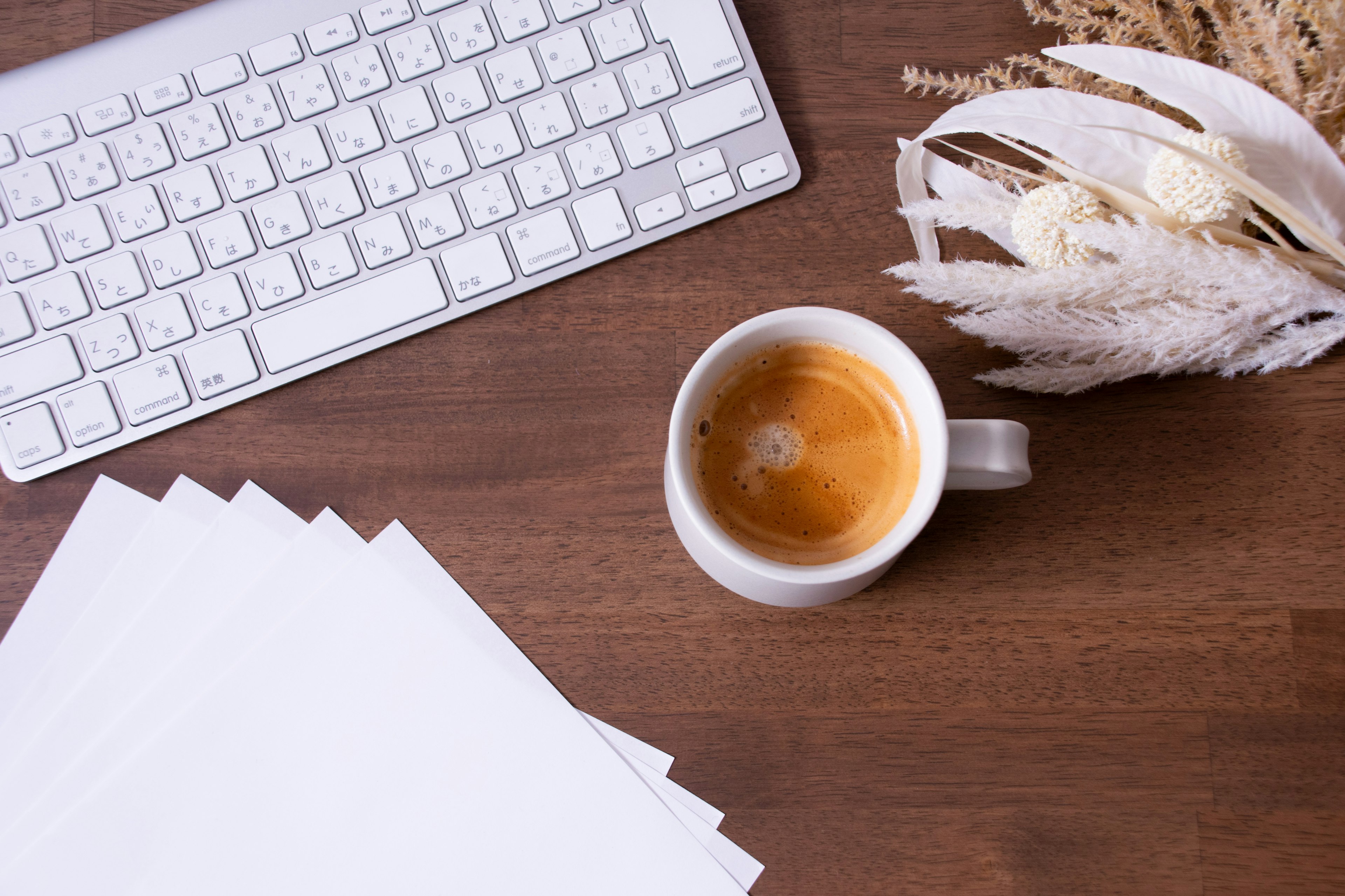 Kaffeetasse auf einem Holztisch neben einer weißen Tastatur