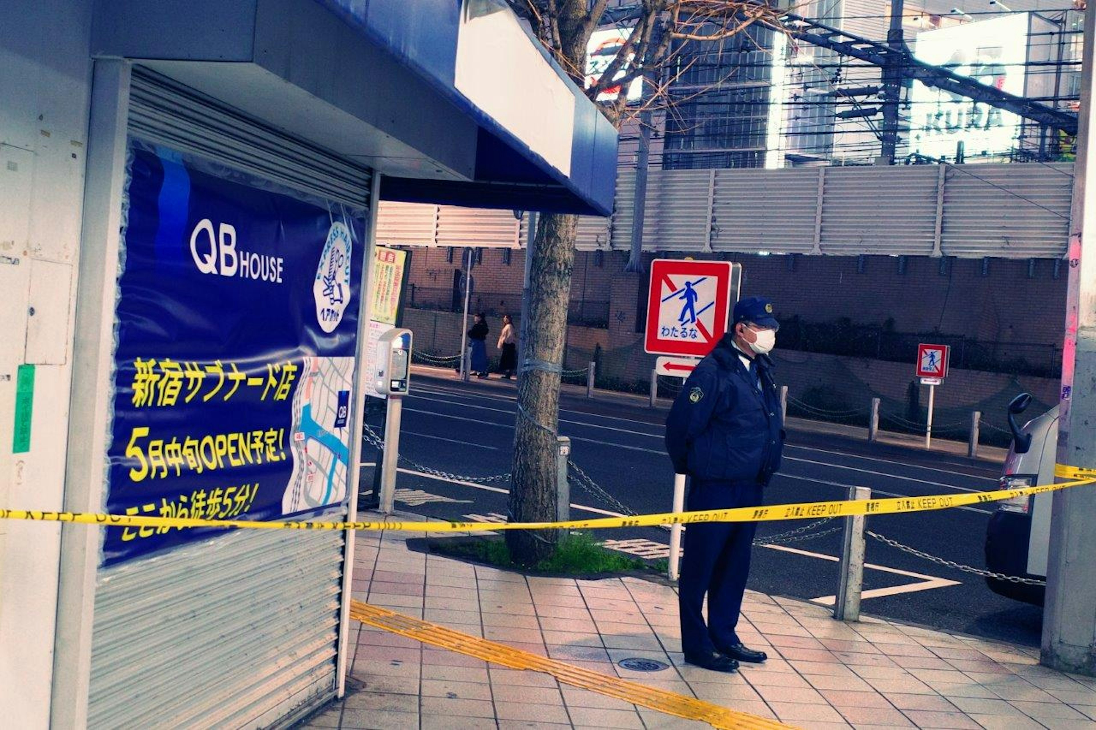 Scene of a police officer standing at a street corner with a barrier tape