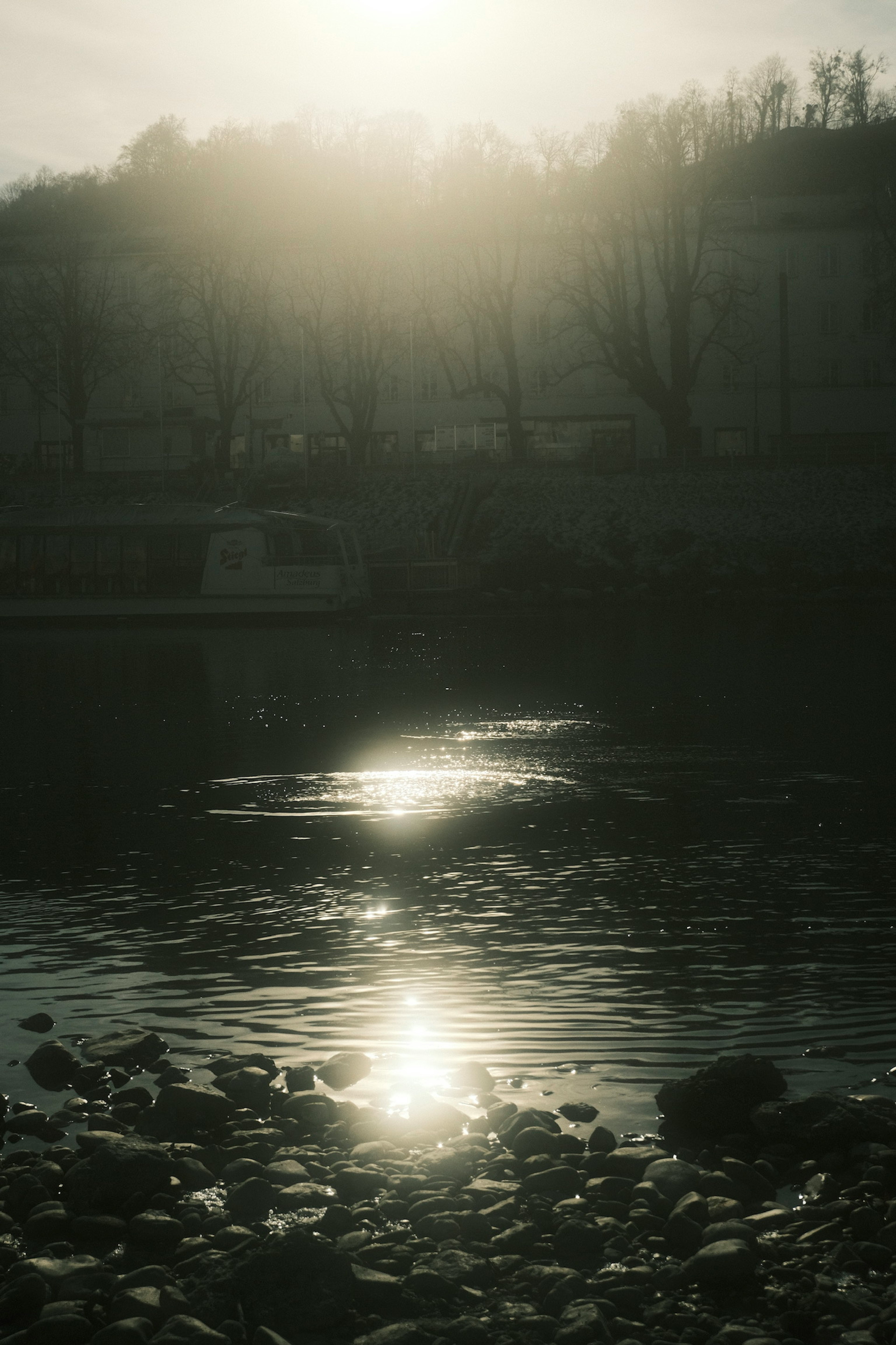 Sanfte Sonnenstrahlen spiegeln sich auf der Wasseroberfläche mit einem steinigen Ufer