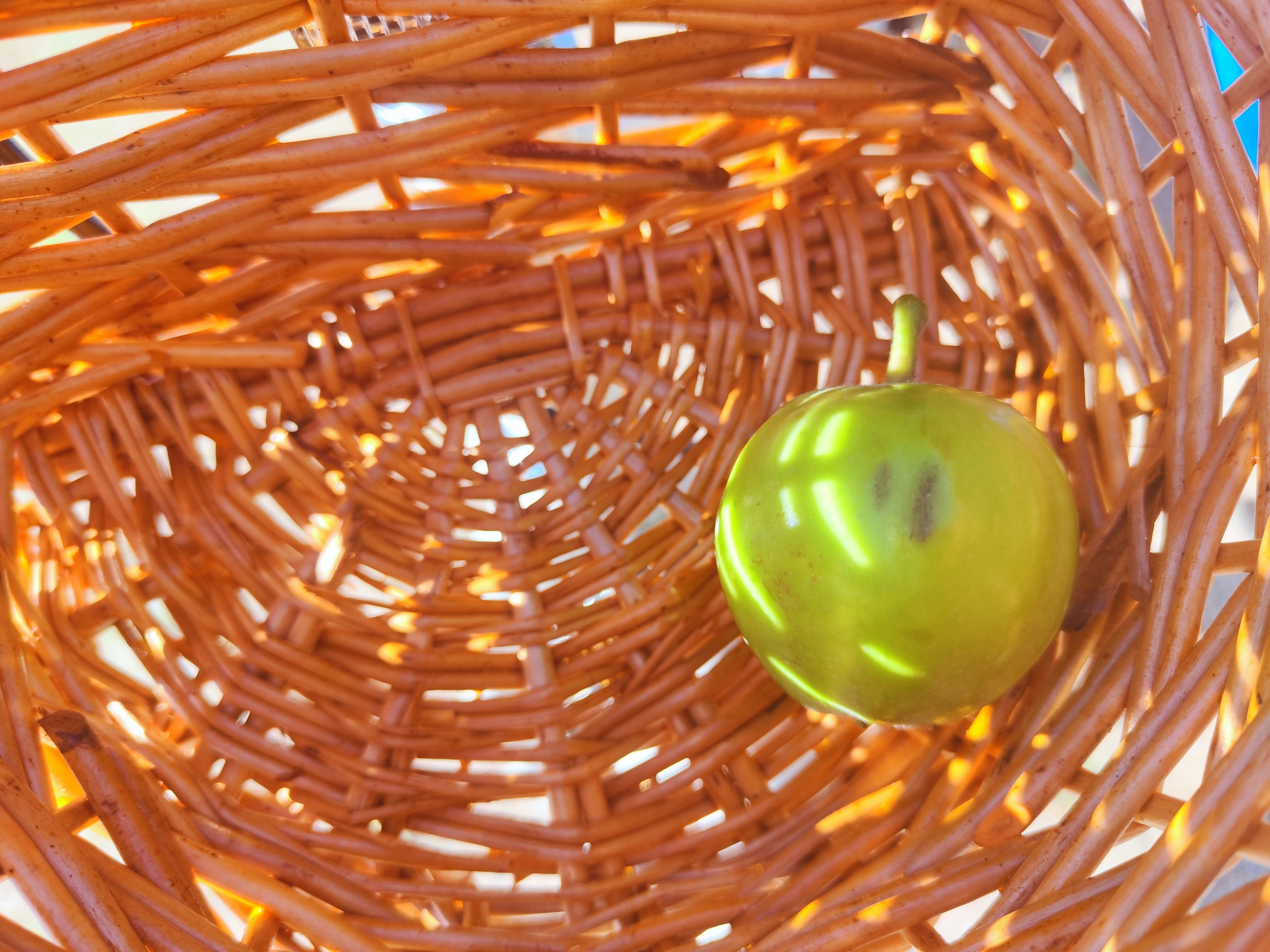 Shiny green apple inside an orange woven basket