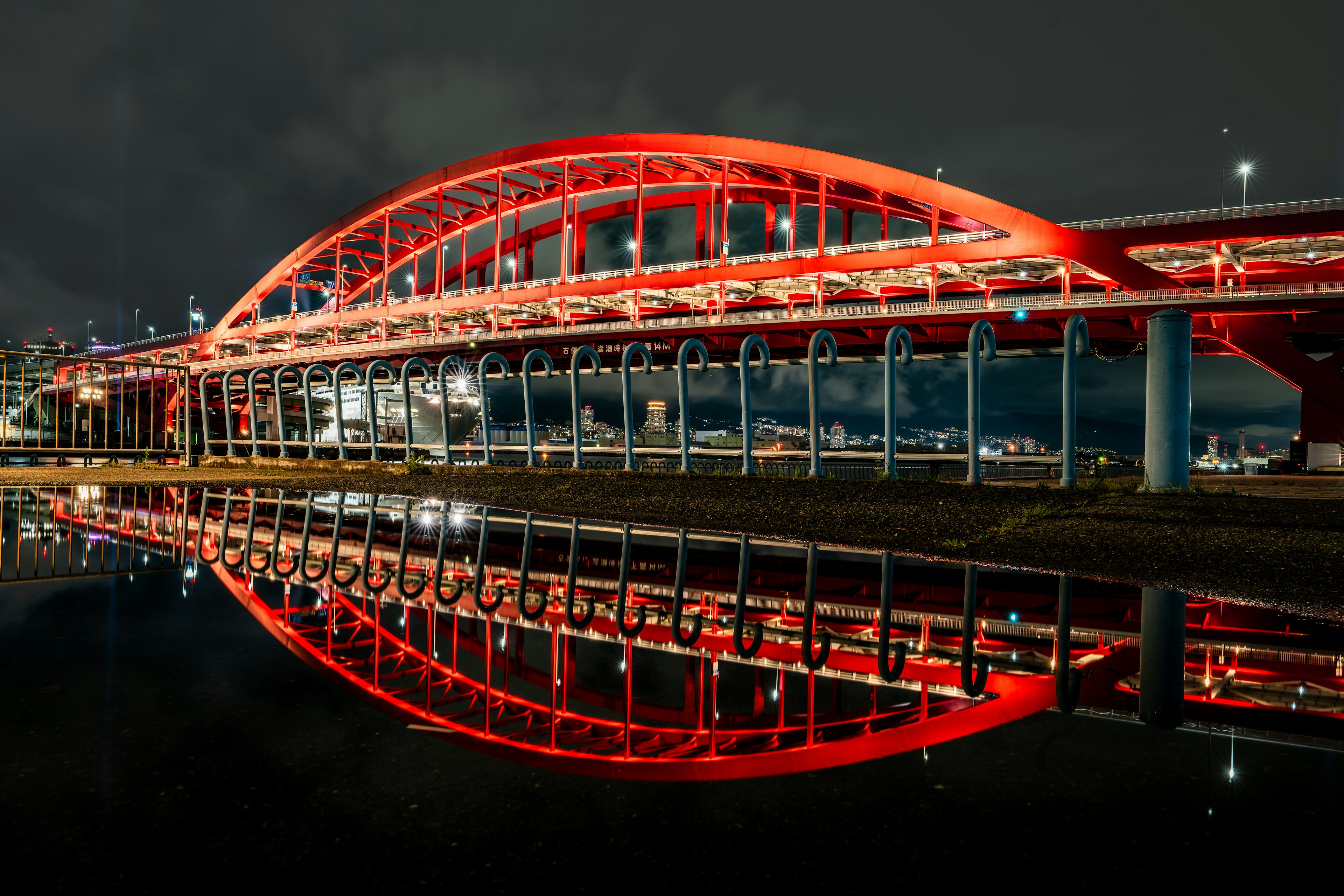 Red arch bridge reflecting on water at night