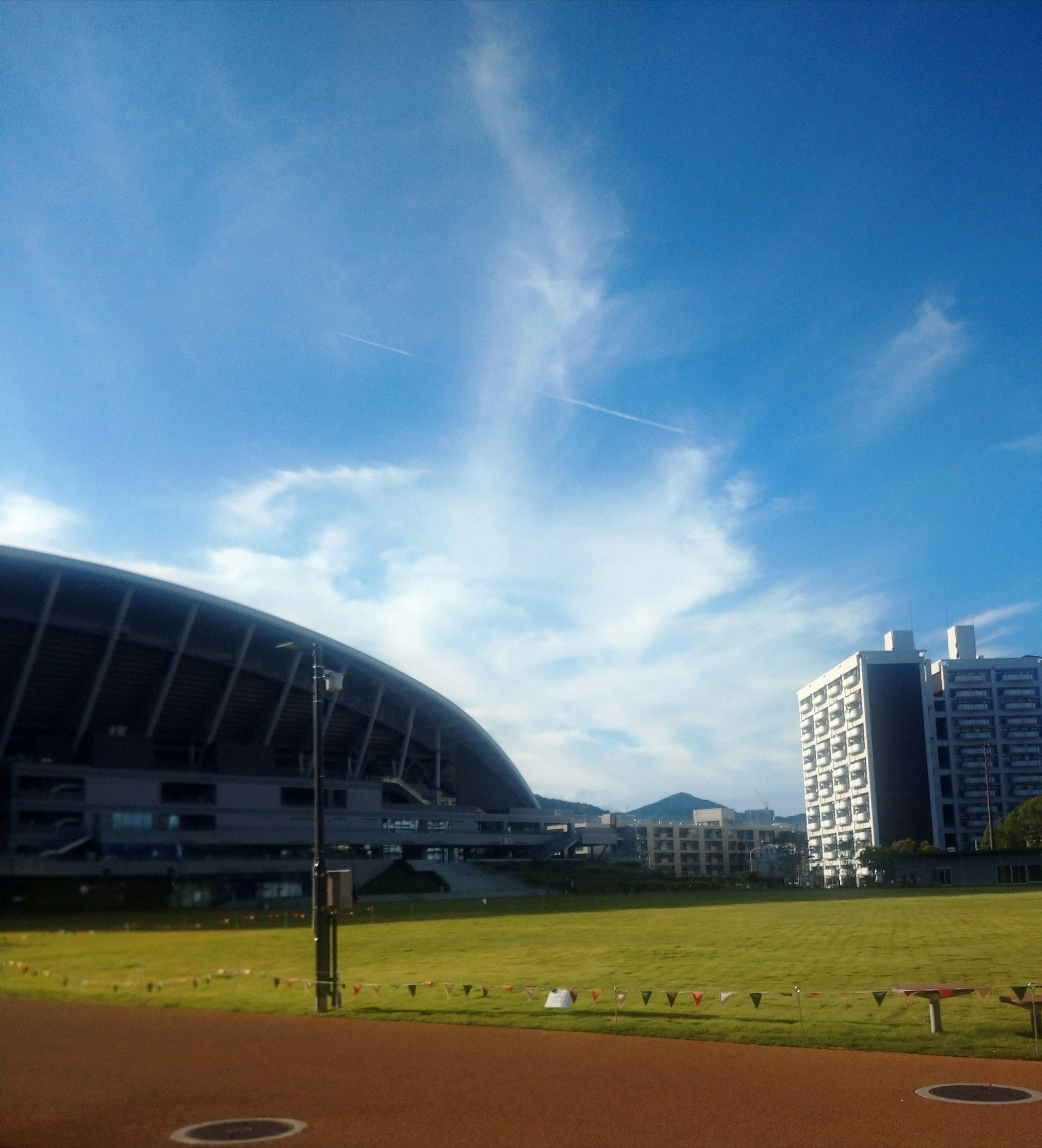 青空と雲が広がるスポーツスタジアムの風景