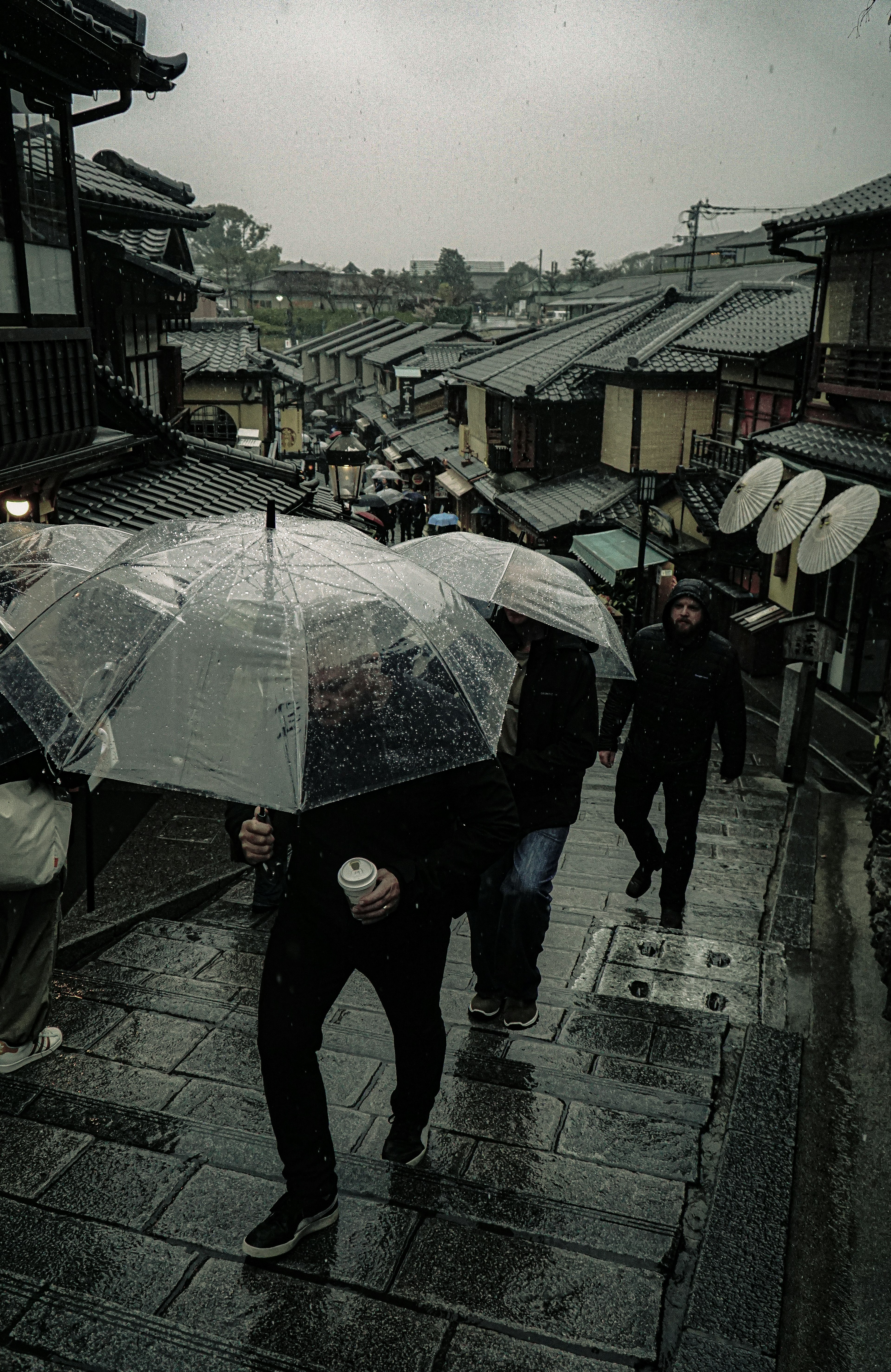 雨の中を歩く人々と傘のある風景 古い街並みが見える