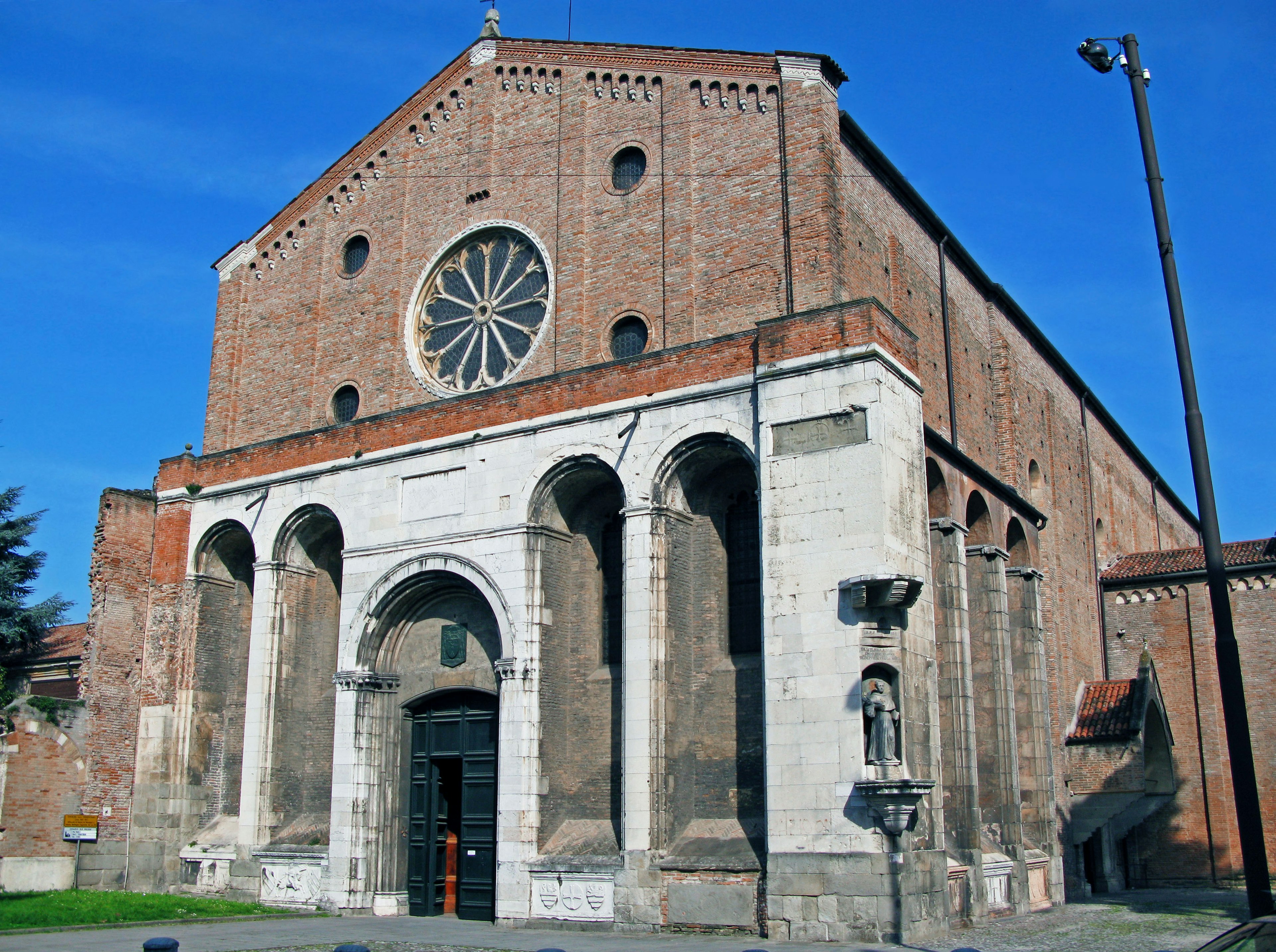 Exterior view of a church featuring a red brick facade and large rose window