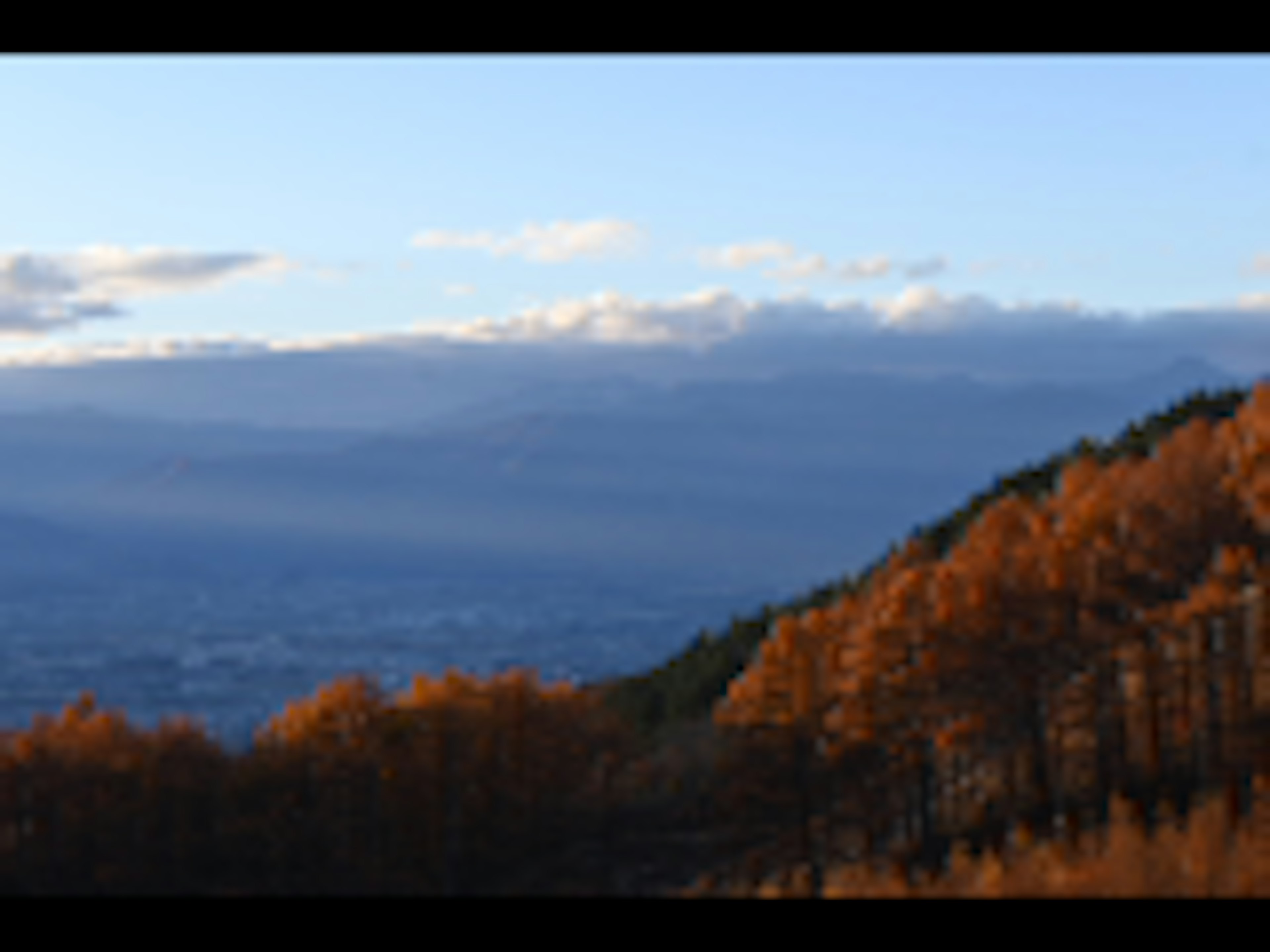 秋の山々と青空の景色オレンジ色の木々と遠くの山々