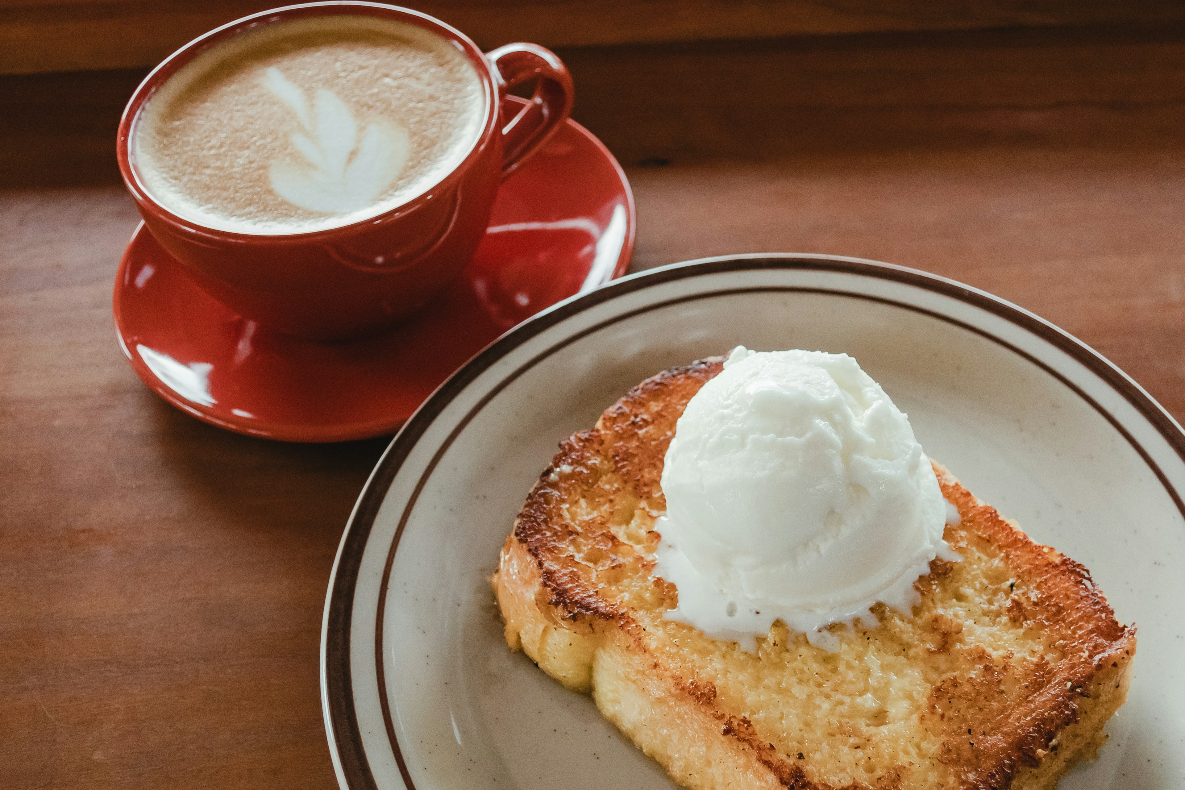 Tostada de postre cubierta con helado y un latte en una taza roja