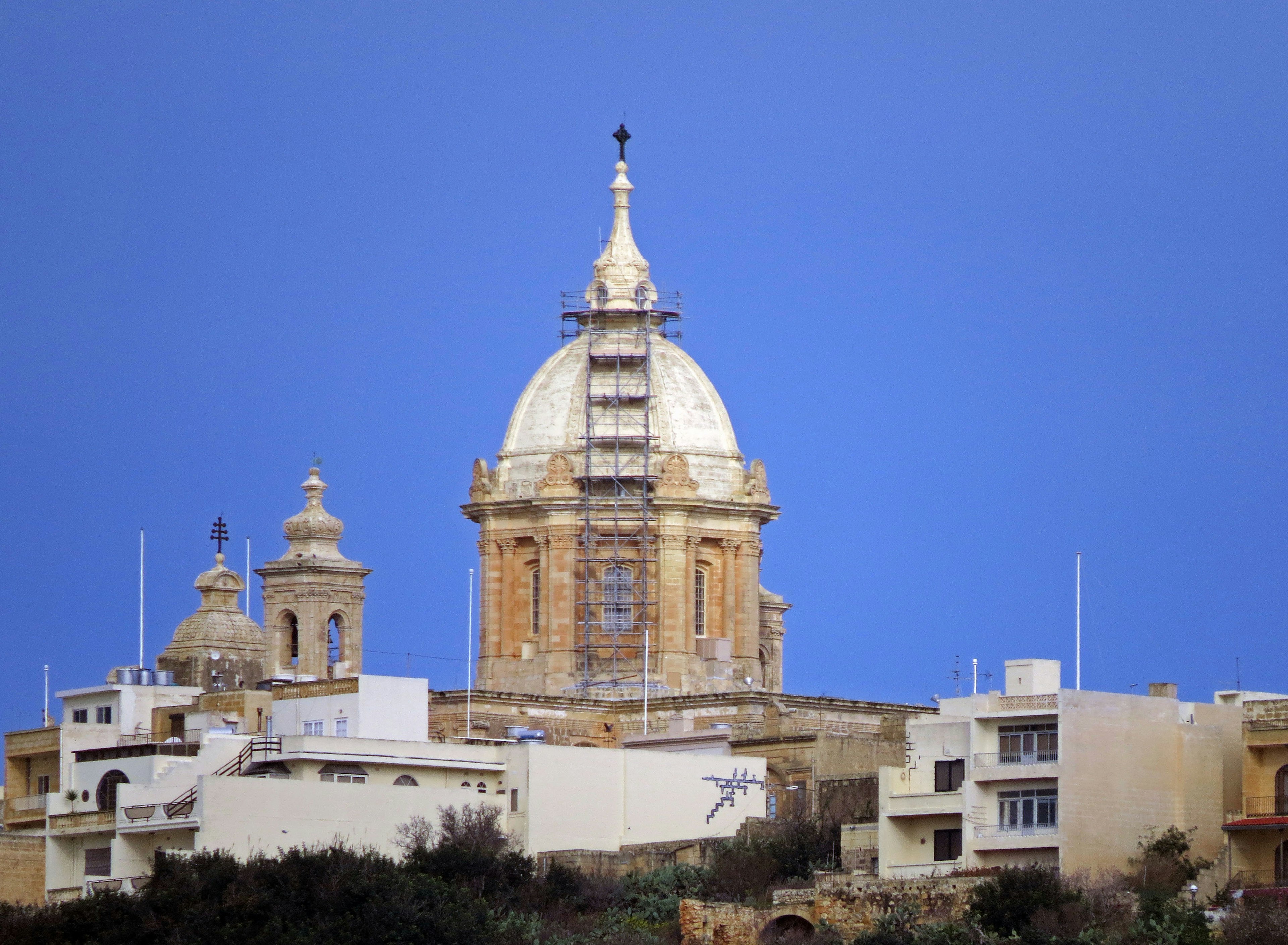 Restoration of a church dome under a beautiful blue sky with surrounding buildings